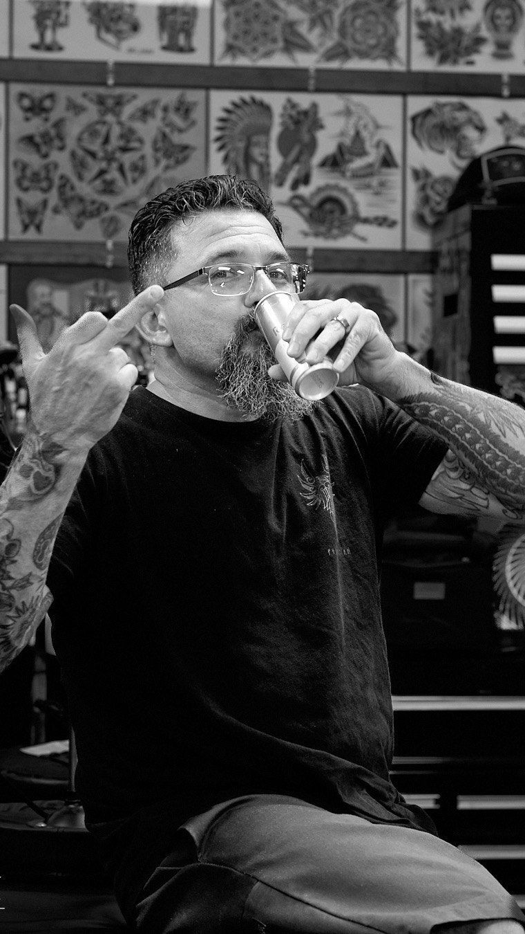 A man with a beard and glasses is drinking from a glass in a black and white photo.