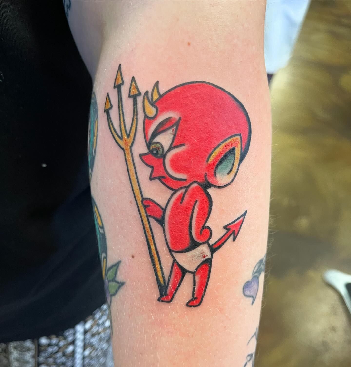 A tattoo of a baby devil holding a trident