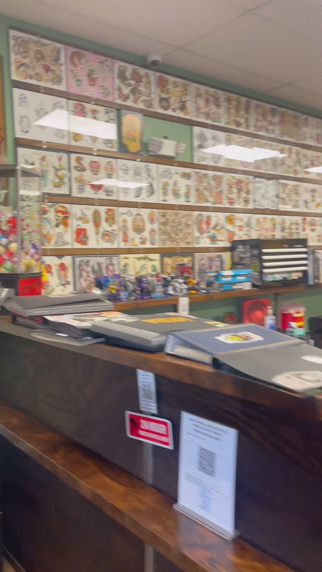 A counter in a tattoo shop with a lot of tattoos on the wall.