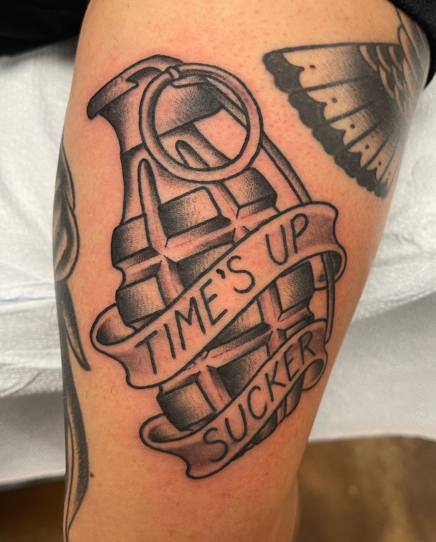 Tattoo of a grenade with a banner reading 