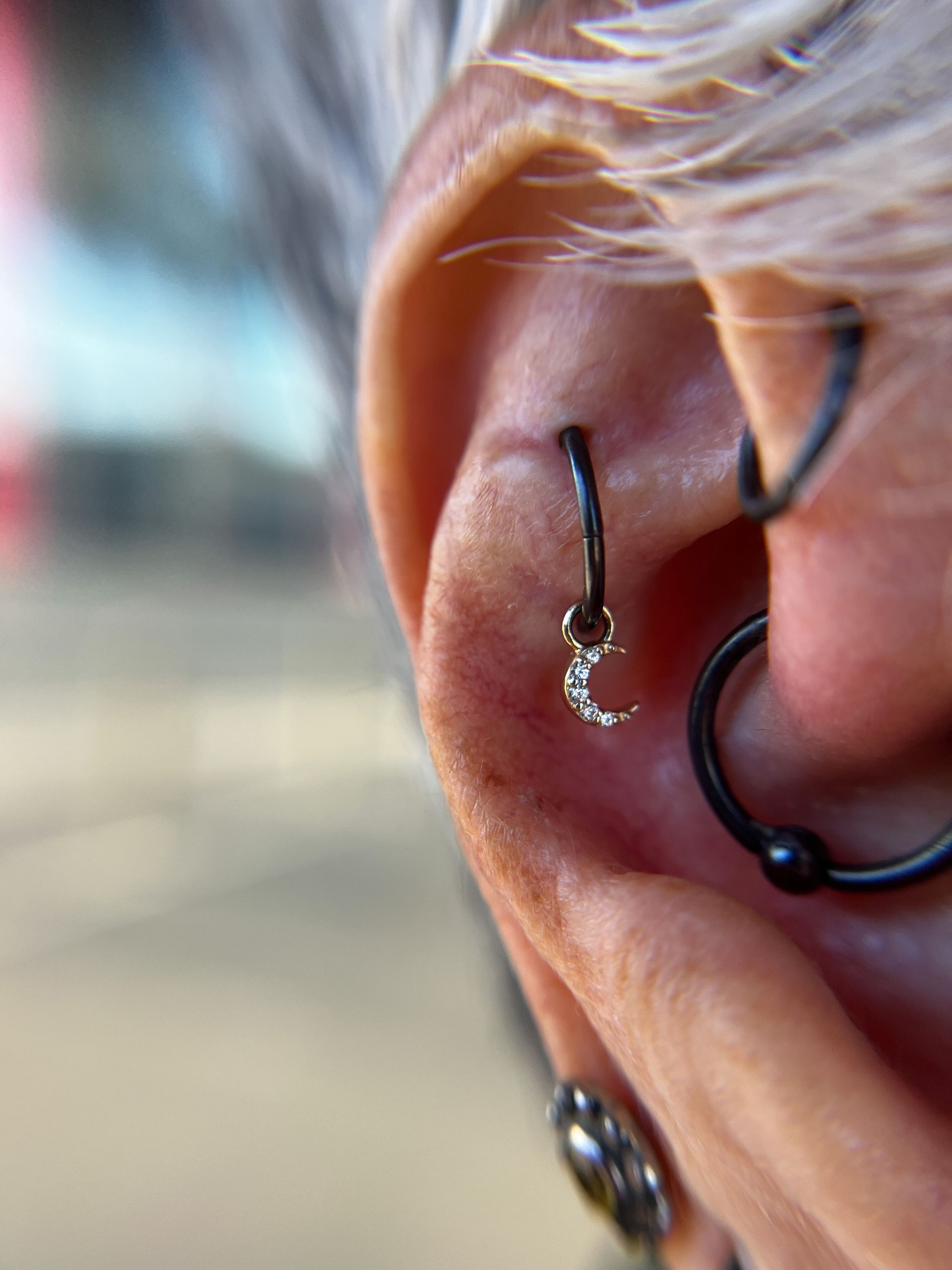 Close-up of an ear with multiple piercings and black hoop and stud earrings