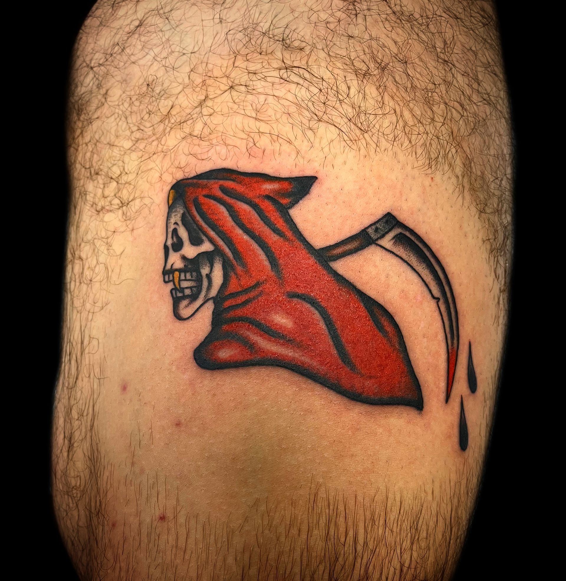 Grim reaper tattoo on skin; skull in red hooded cloak with sickle, blood drops.