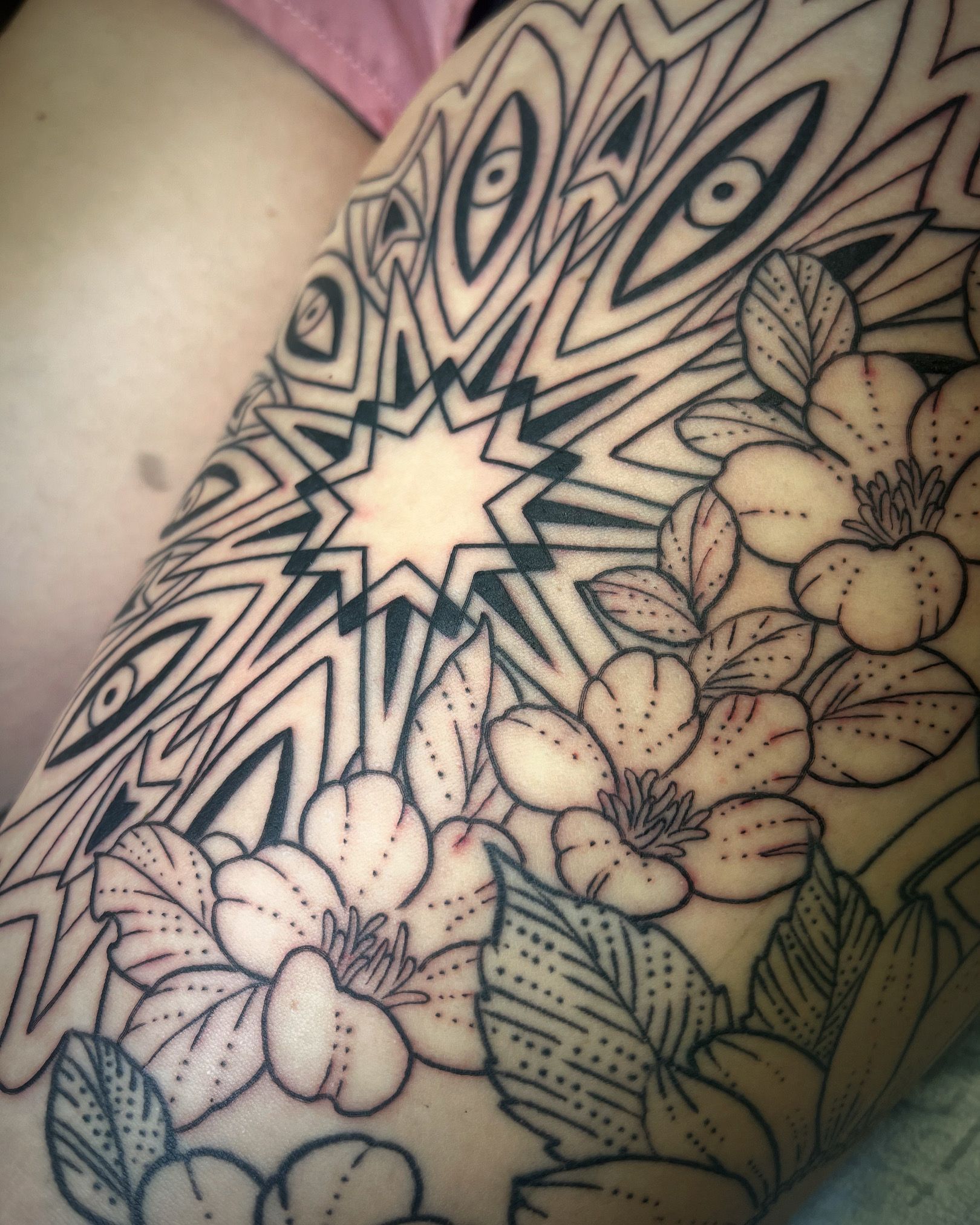 Black and white tattoo of a floral design with a geometric starburst pattern.