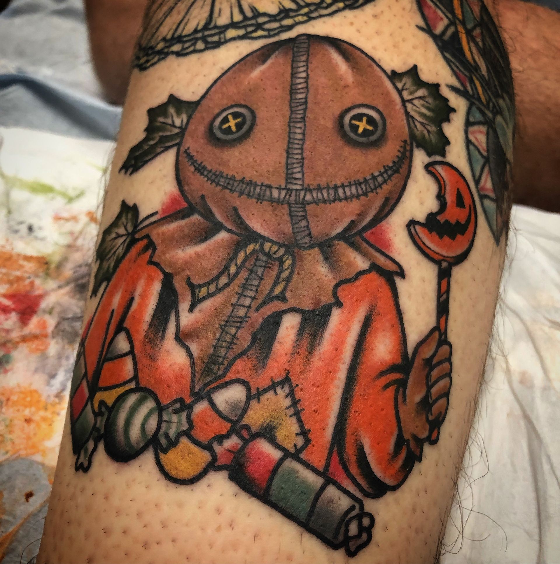 Tattoo of a character from Trick 'r Treat, holding a candy, in bright colors.