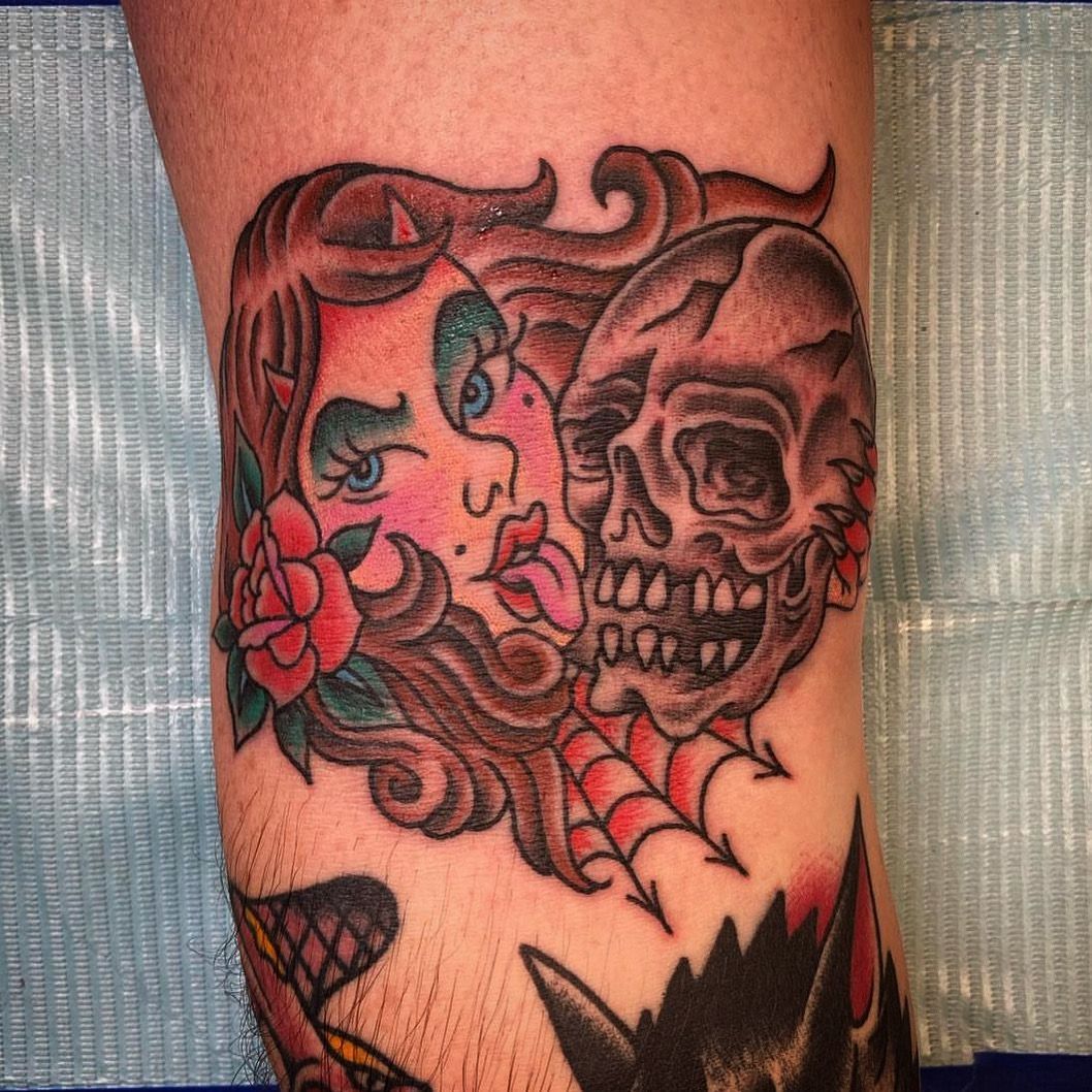 Tattoo of a woman's face and skull. Red rose, web, and pink lips. Brown, red, and black ink on skin.