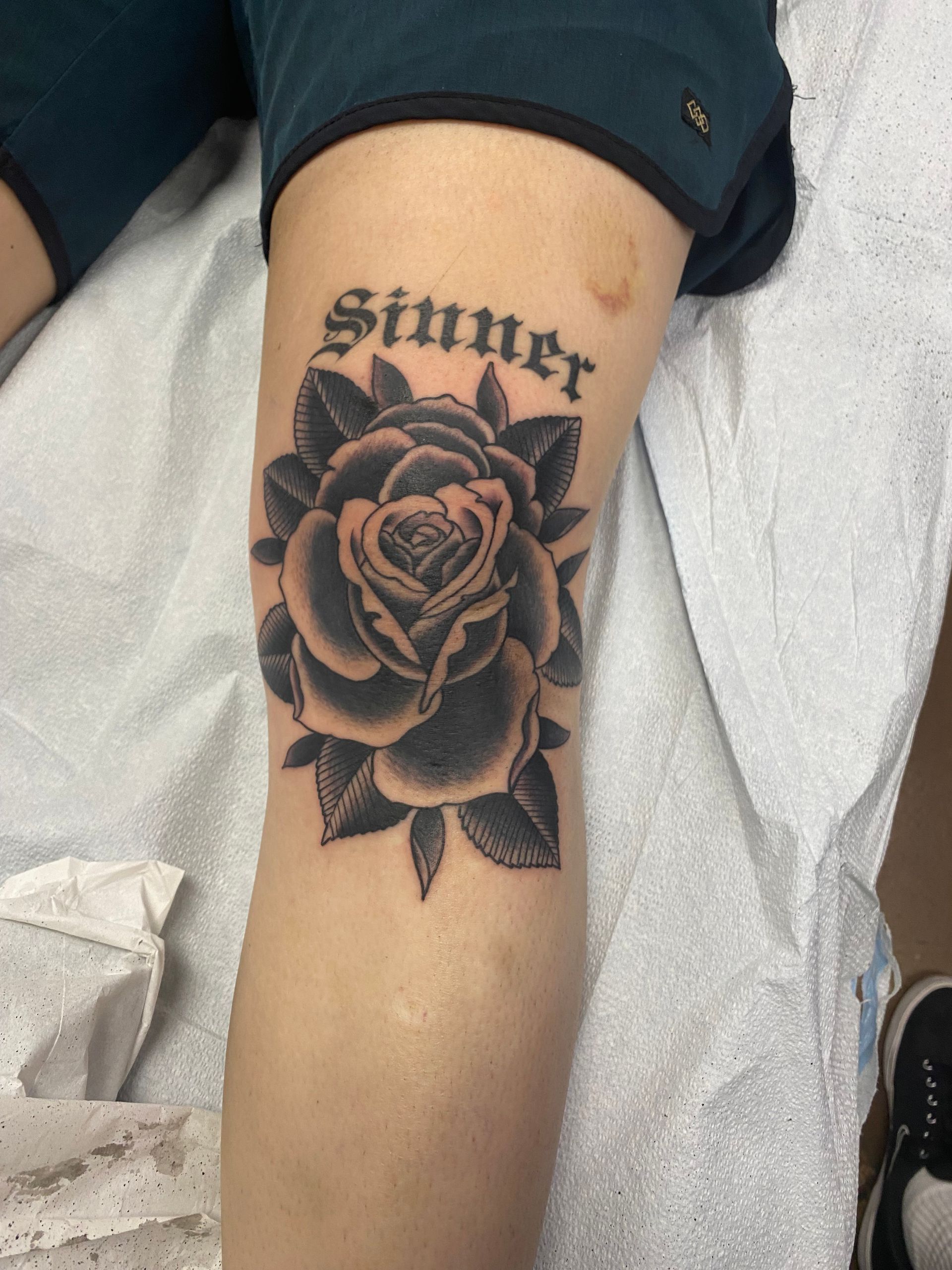 Tattoo of a black rose and the word 