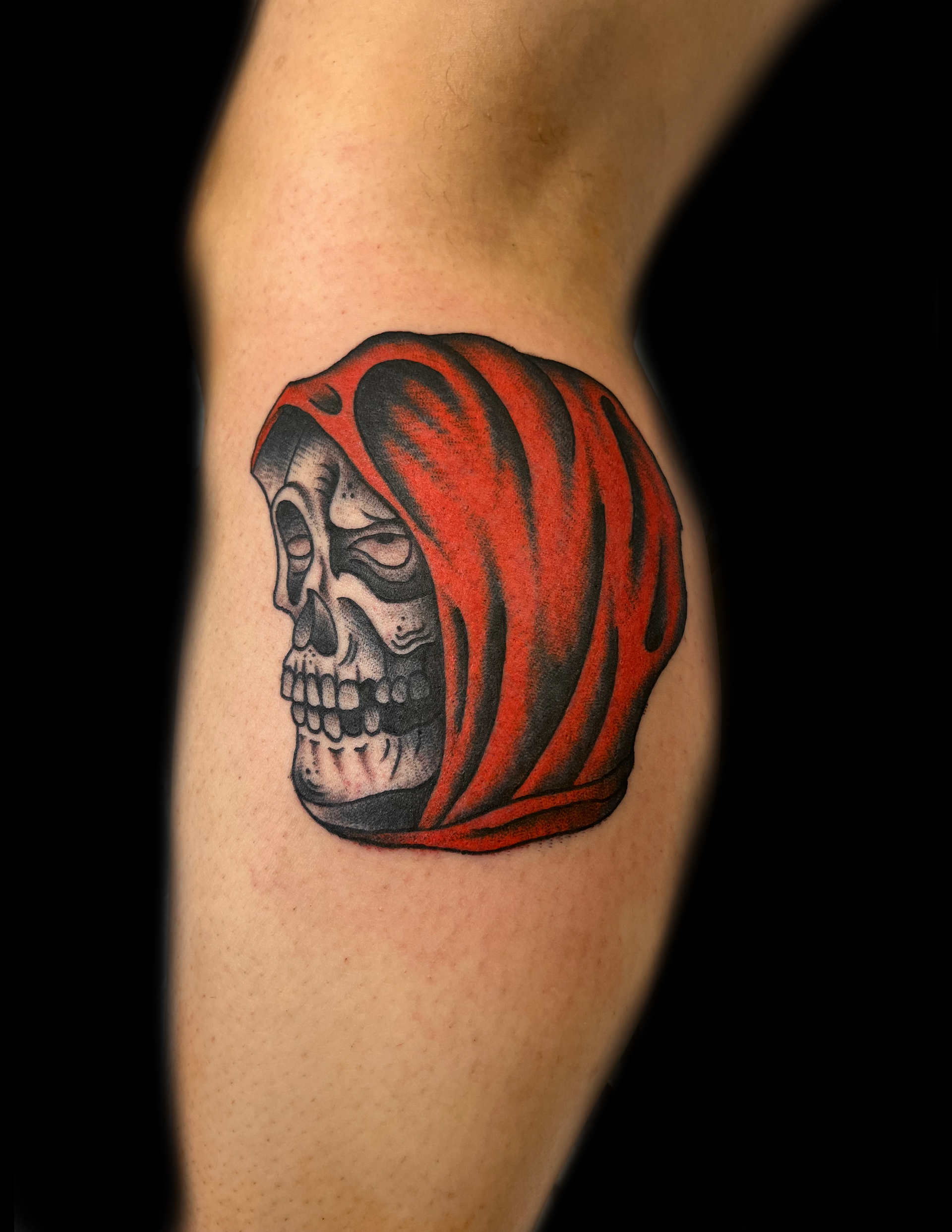 Skull tattoo with red hood on leg.