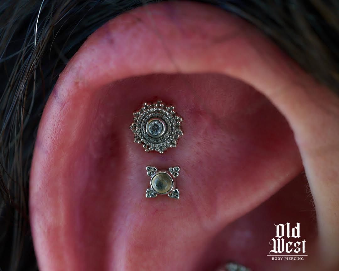 Ear piercing with two ornate silver jewelry pieces.