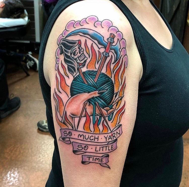 Tattoo of a grim reaper with knitting needles stabbing a yarn ball amidst flames, 