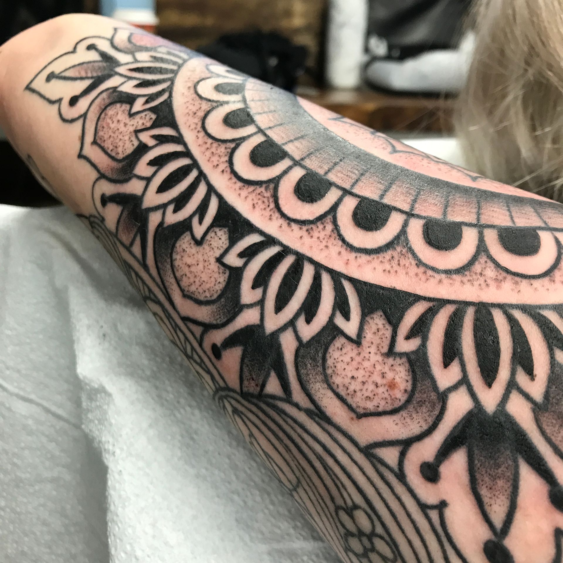 Black and gray mandala tattoo on forearm, intricate details and shading.