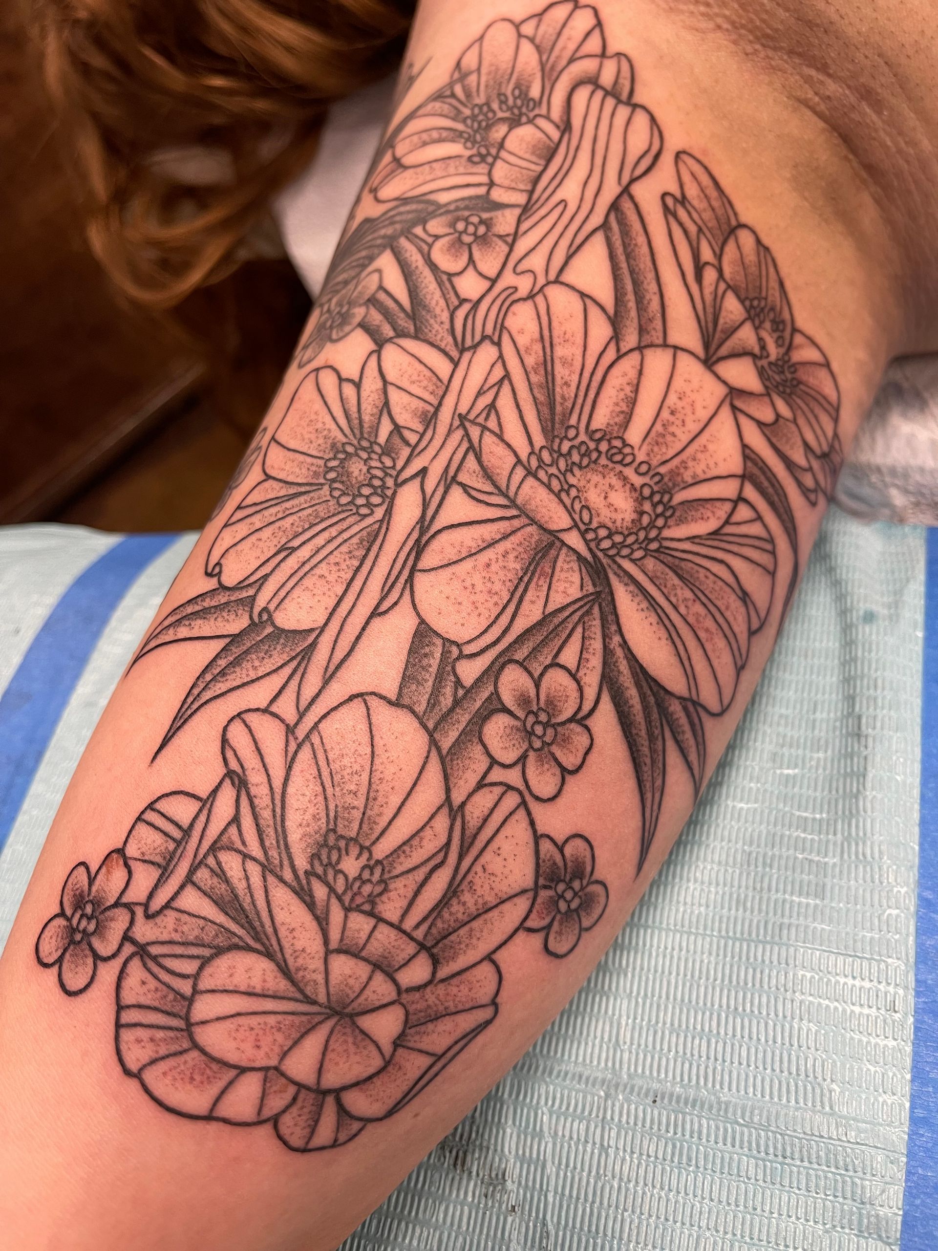 Black ink flower tattoo on forearm.