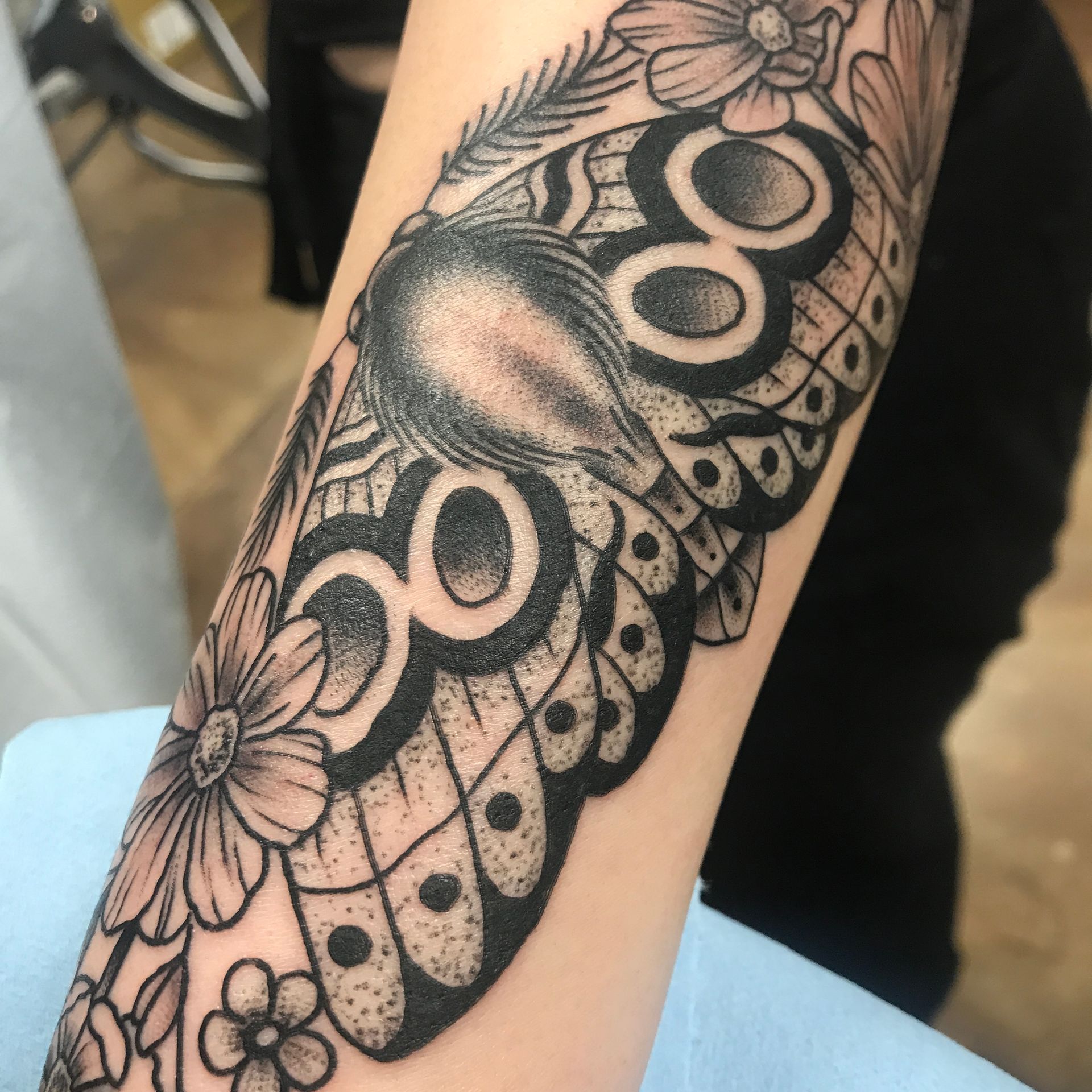 Black ink butterfly and floral tattoo on an arm.