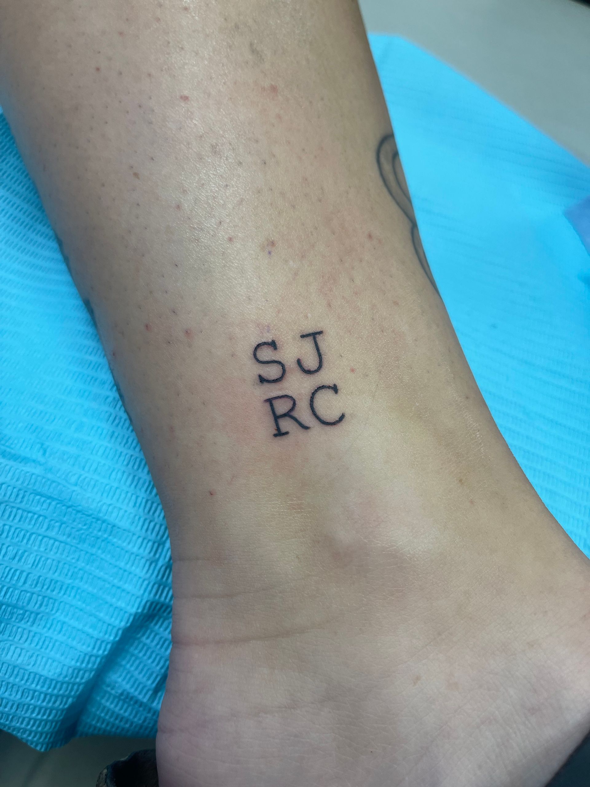 Small tattoo on an ankle, with the initials 