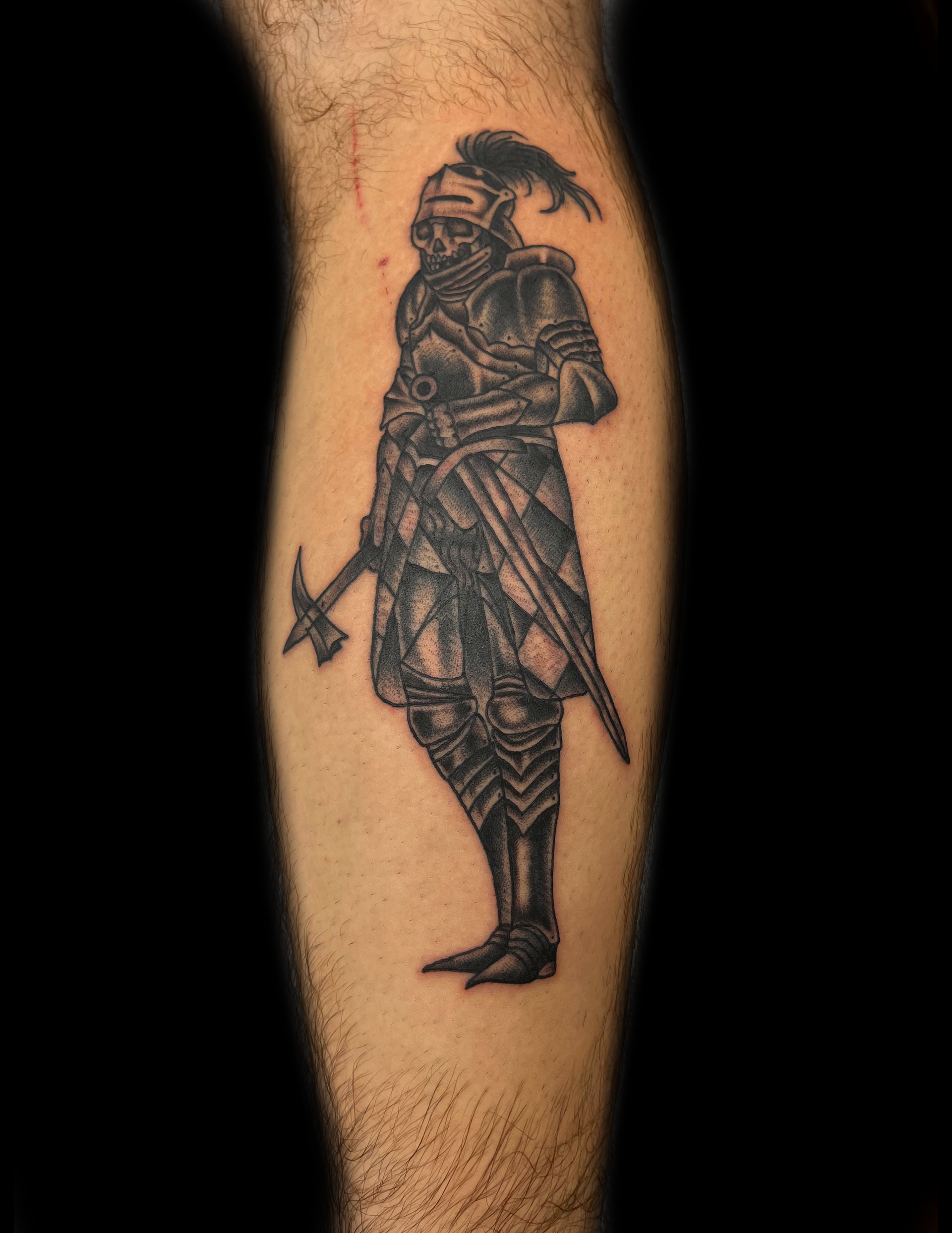 Tattoo of a knight in full armor, holding a war hammer and a sword, on a hairy leg.