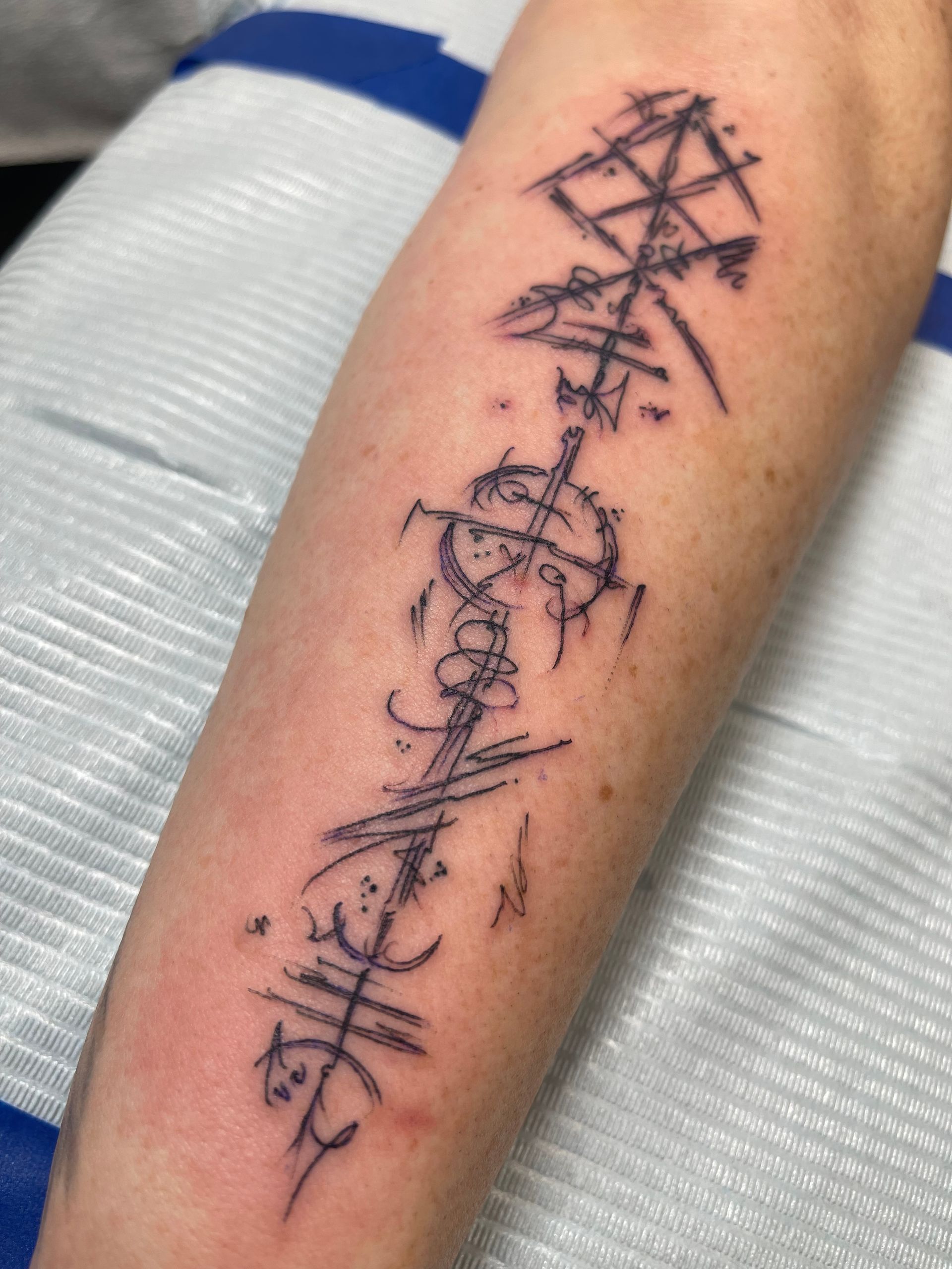Tattoo on arm, abstract line art design in black ink.