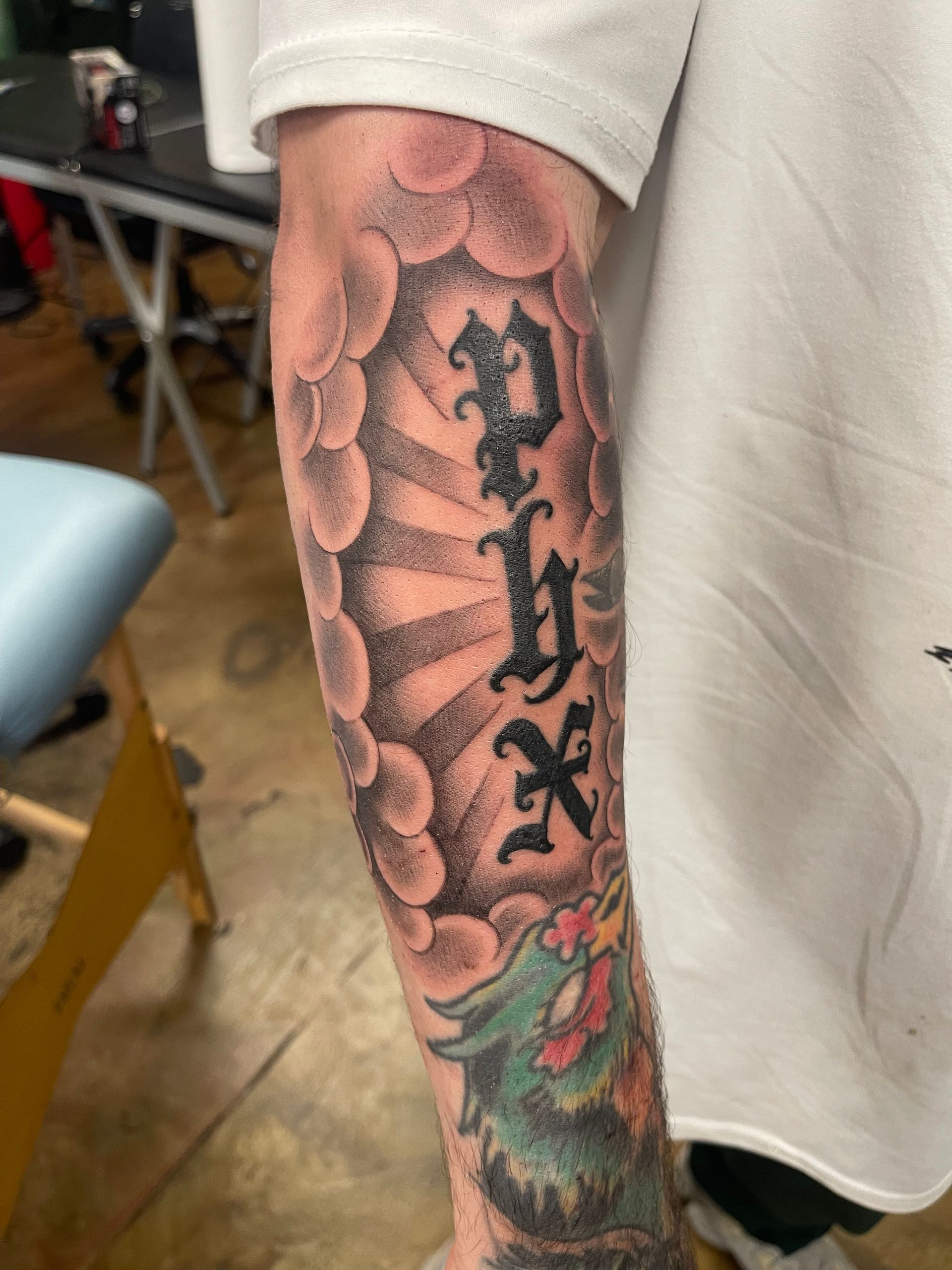 Close-up of a colorful snake tattoo on a forearm with black lettering down the center