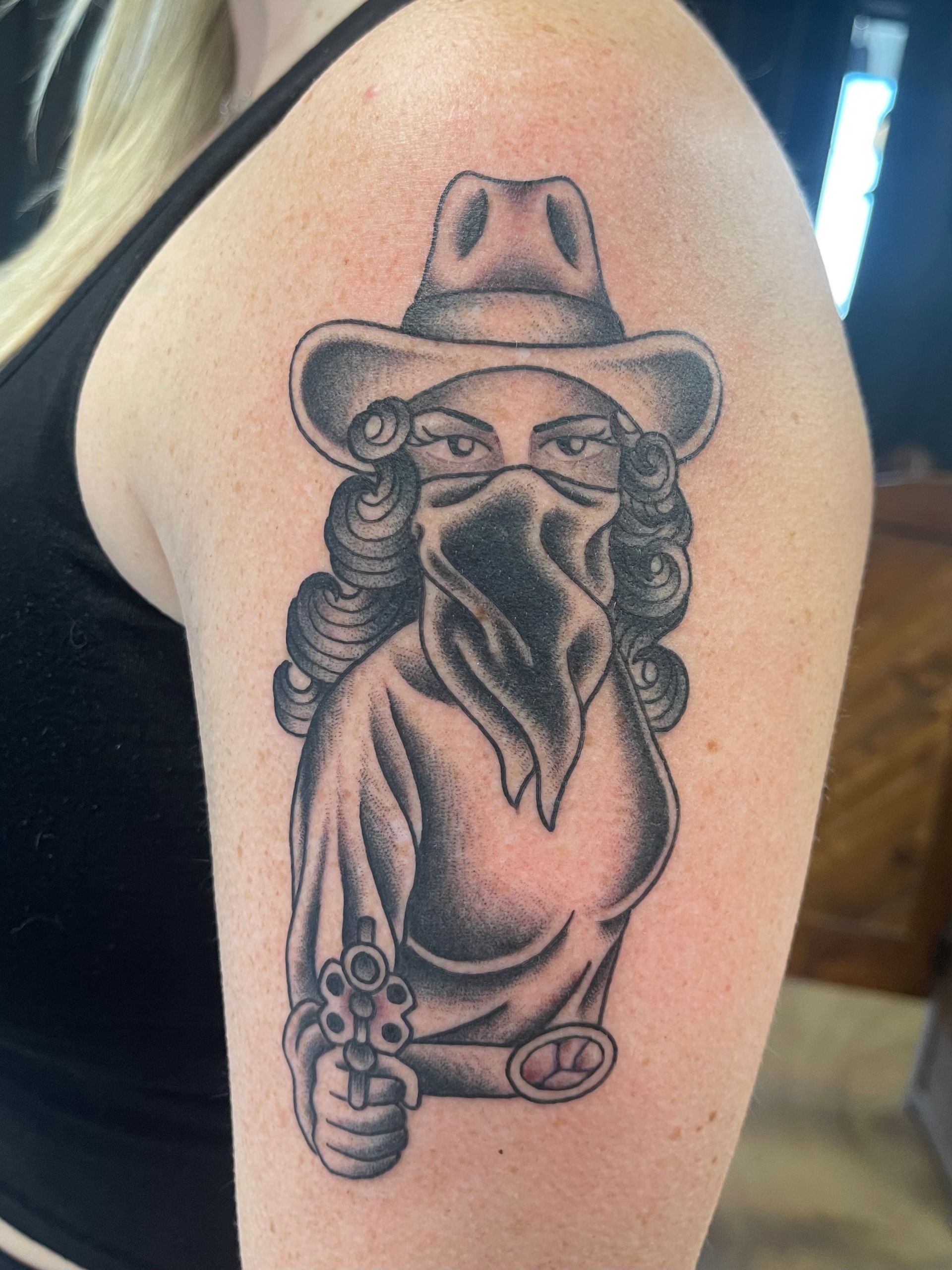 Tattoo of a person in a cowboy hat and bandana, holding a gun.
