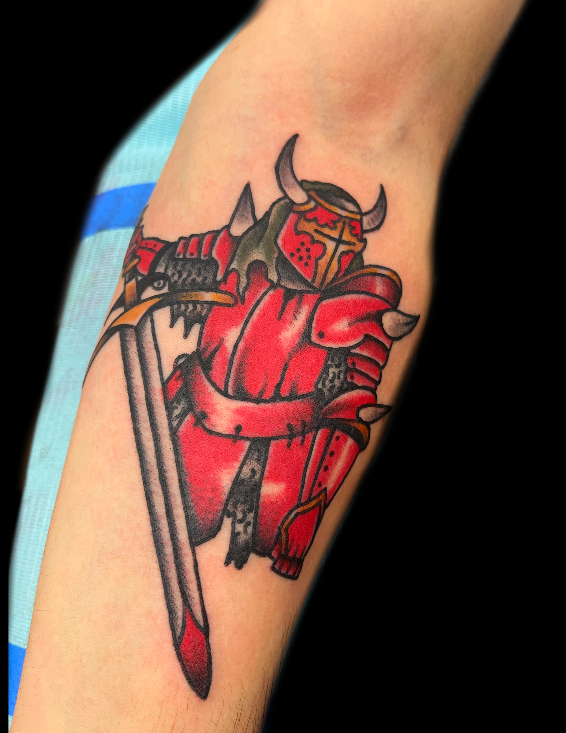 Red knight tattoo on an arm, holding a sword. Black outline with a black background.