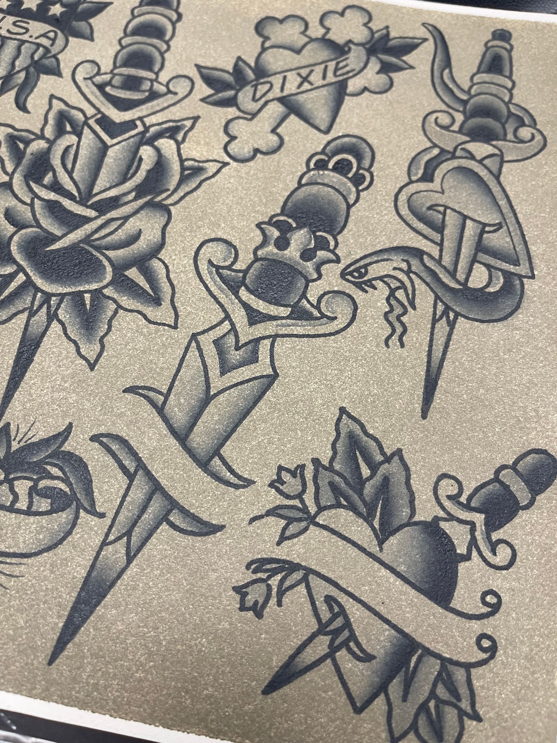 Tattoo flash sheet with traditional designs: roses, daggers, hearts, banners, and a snake.