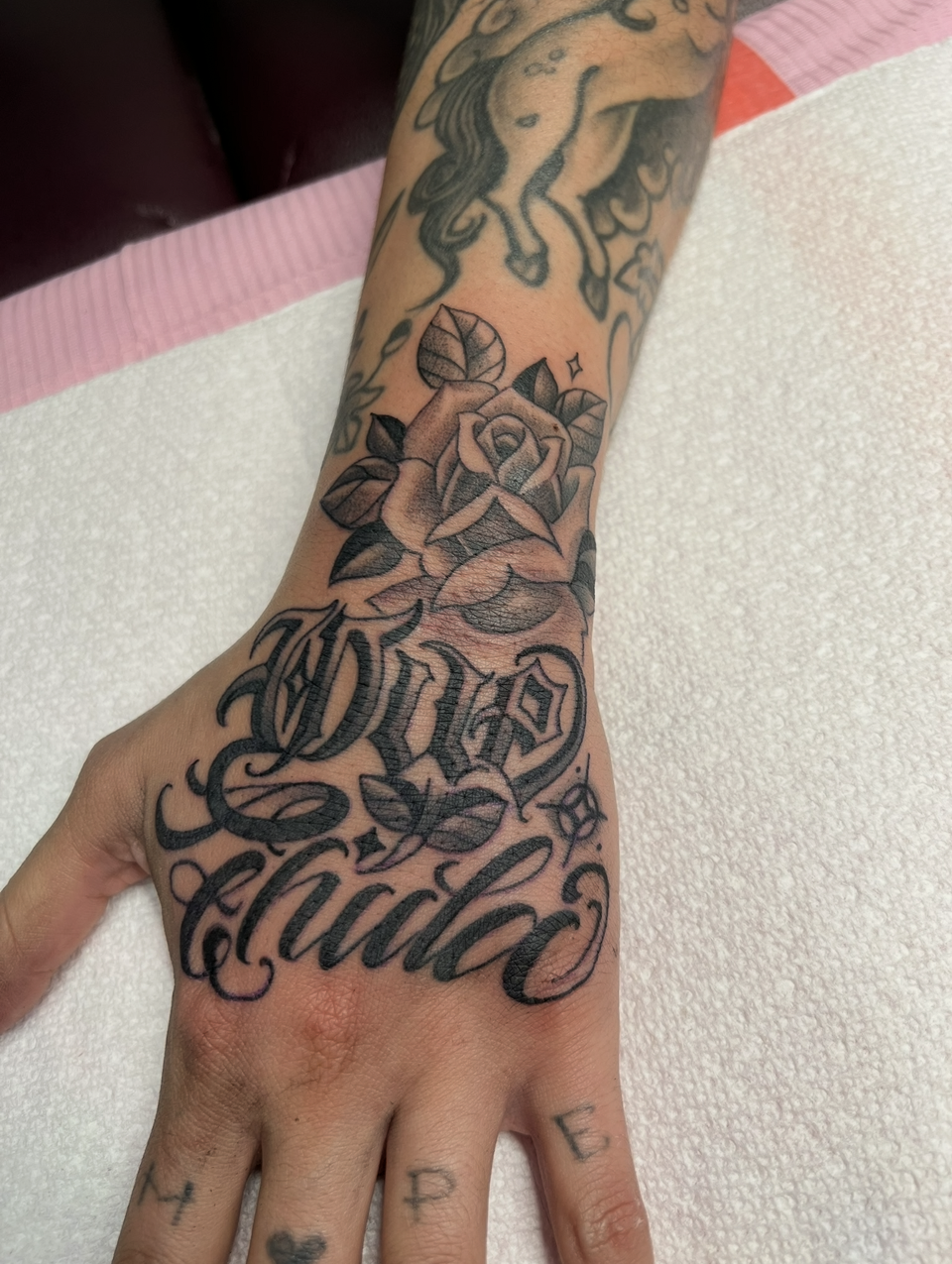 Tattooed hand with floral and script tattoos resting on a white towel