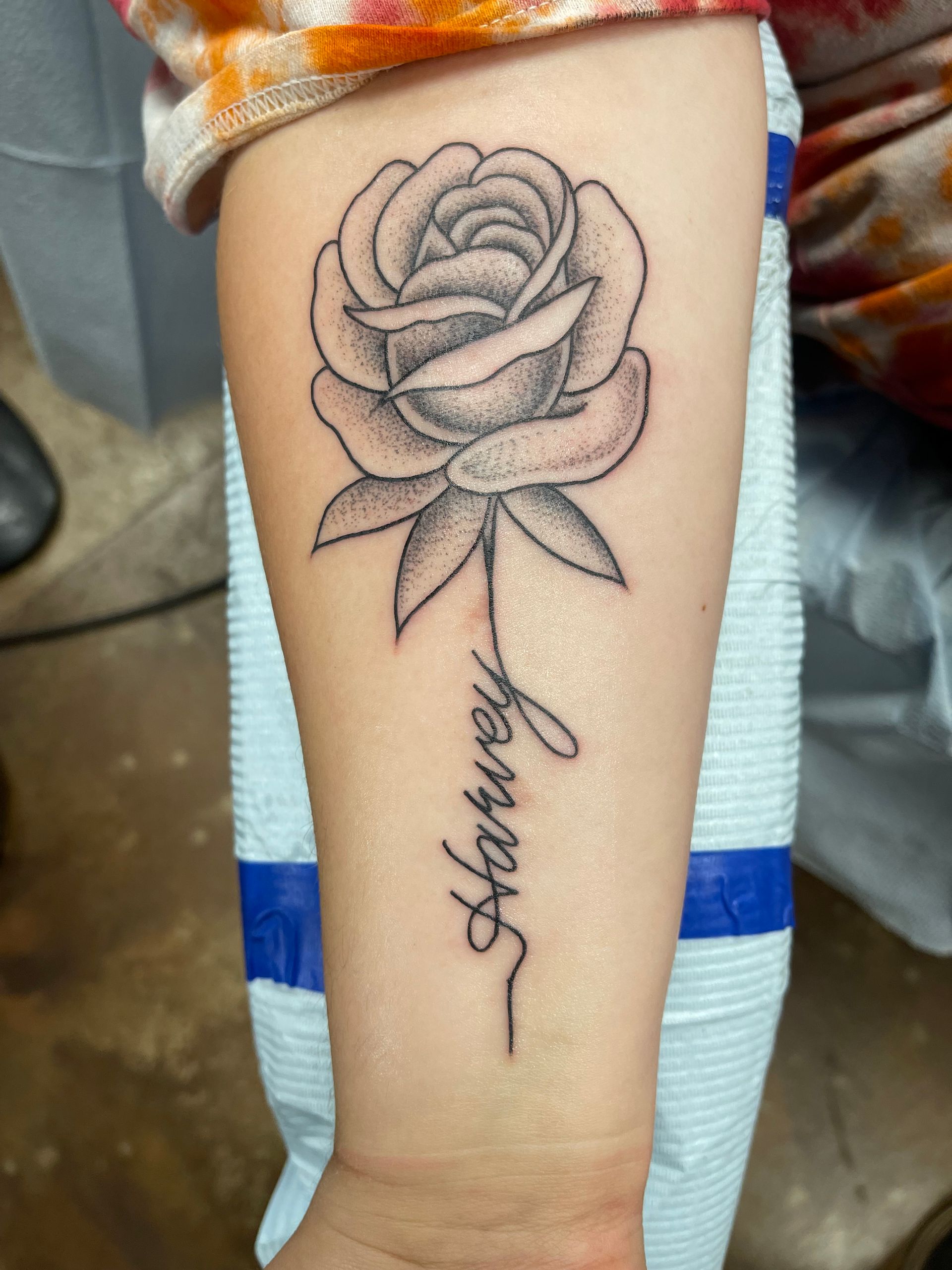 Rose tattoo on forearm with the name 
