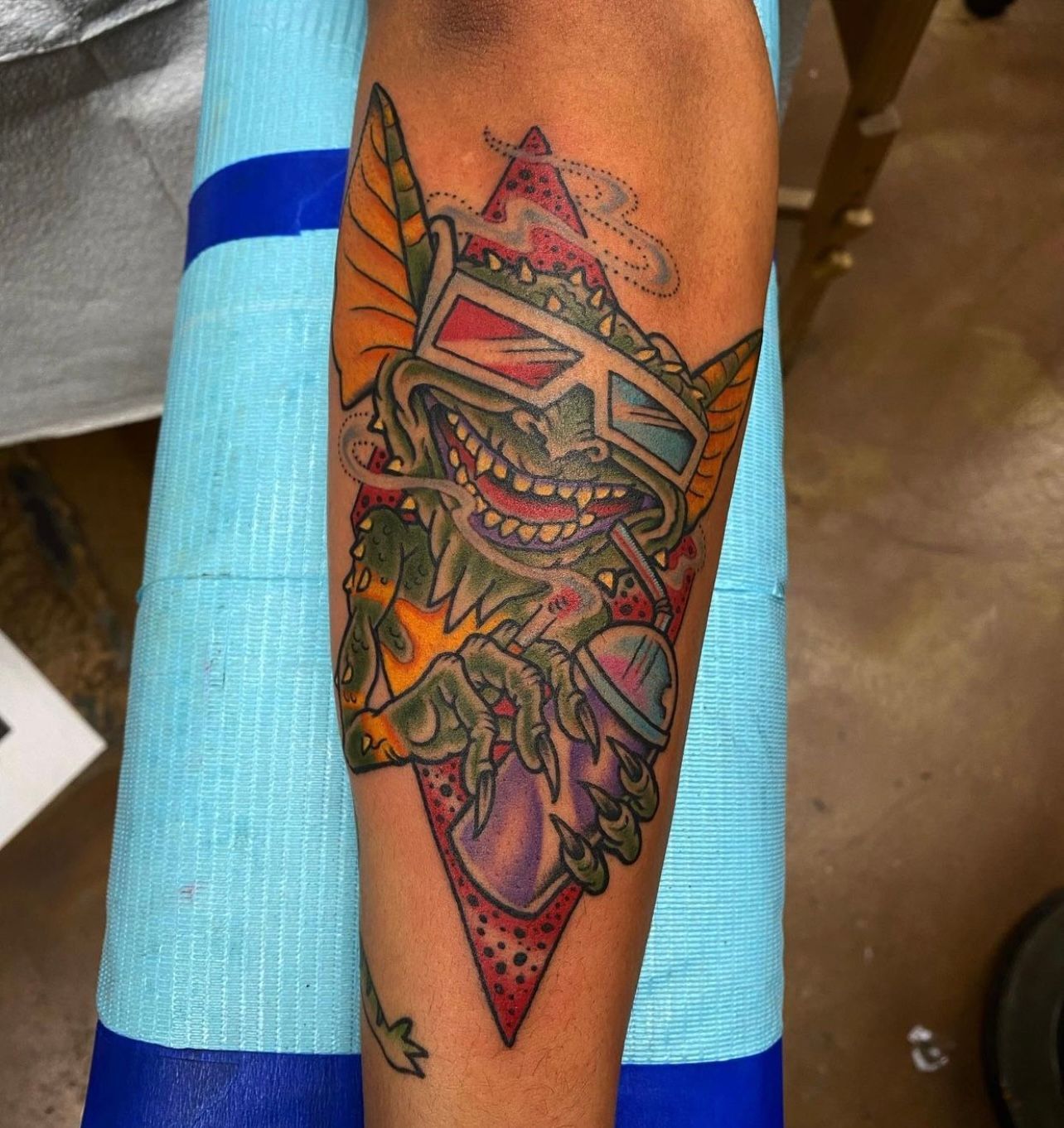Gremlin tattoo wearing 3D glasses, smoking, and holding spray paint.