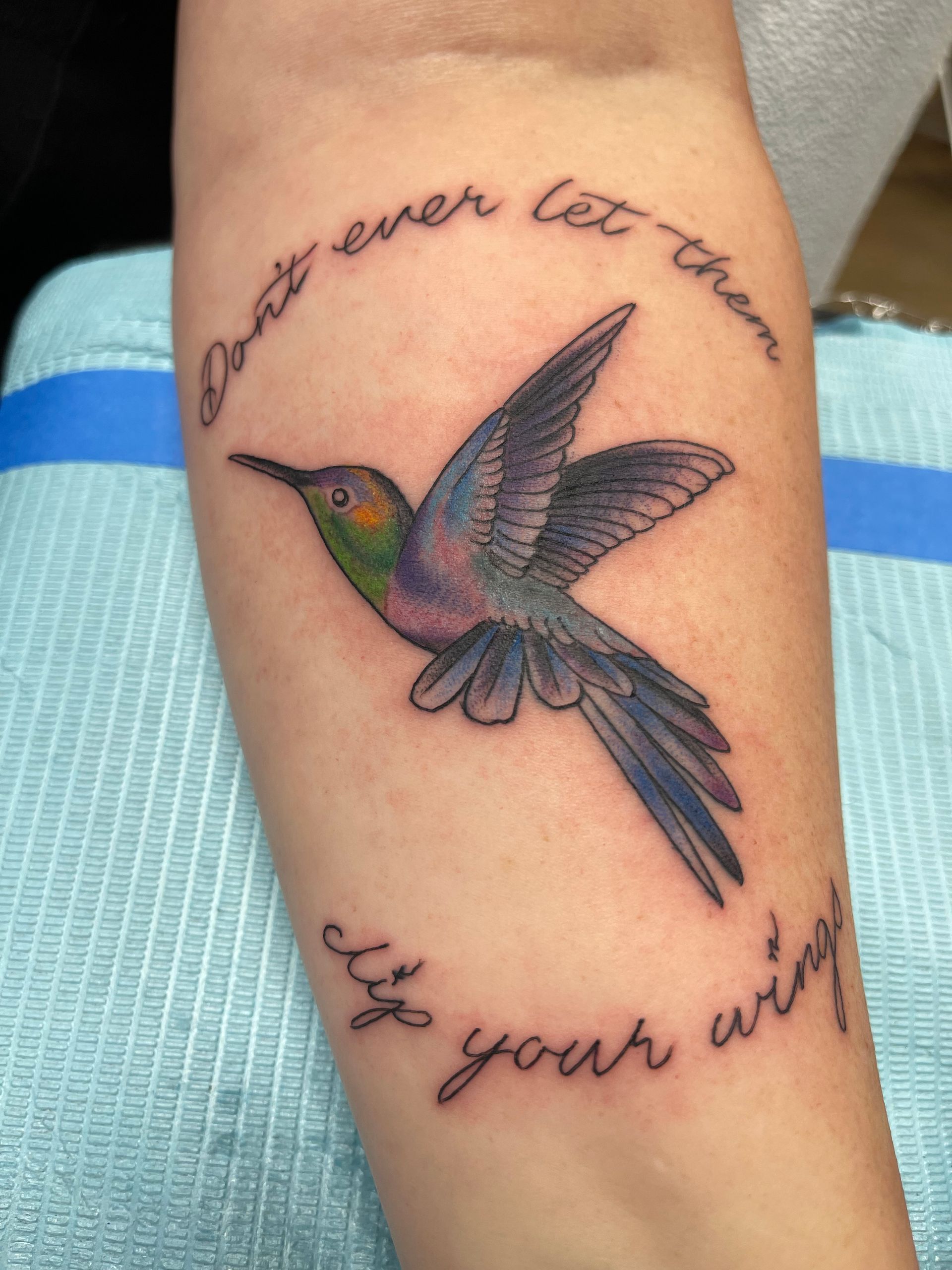 A hummingbird tattoo in flight, with surrounding text: 