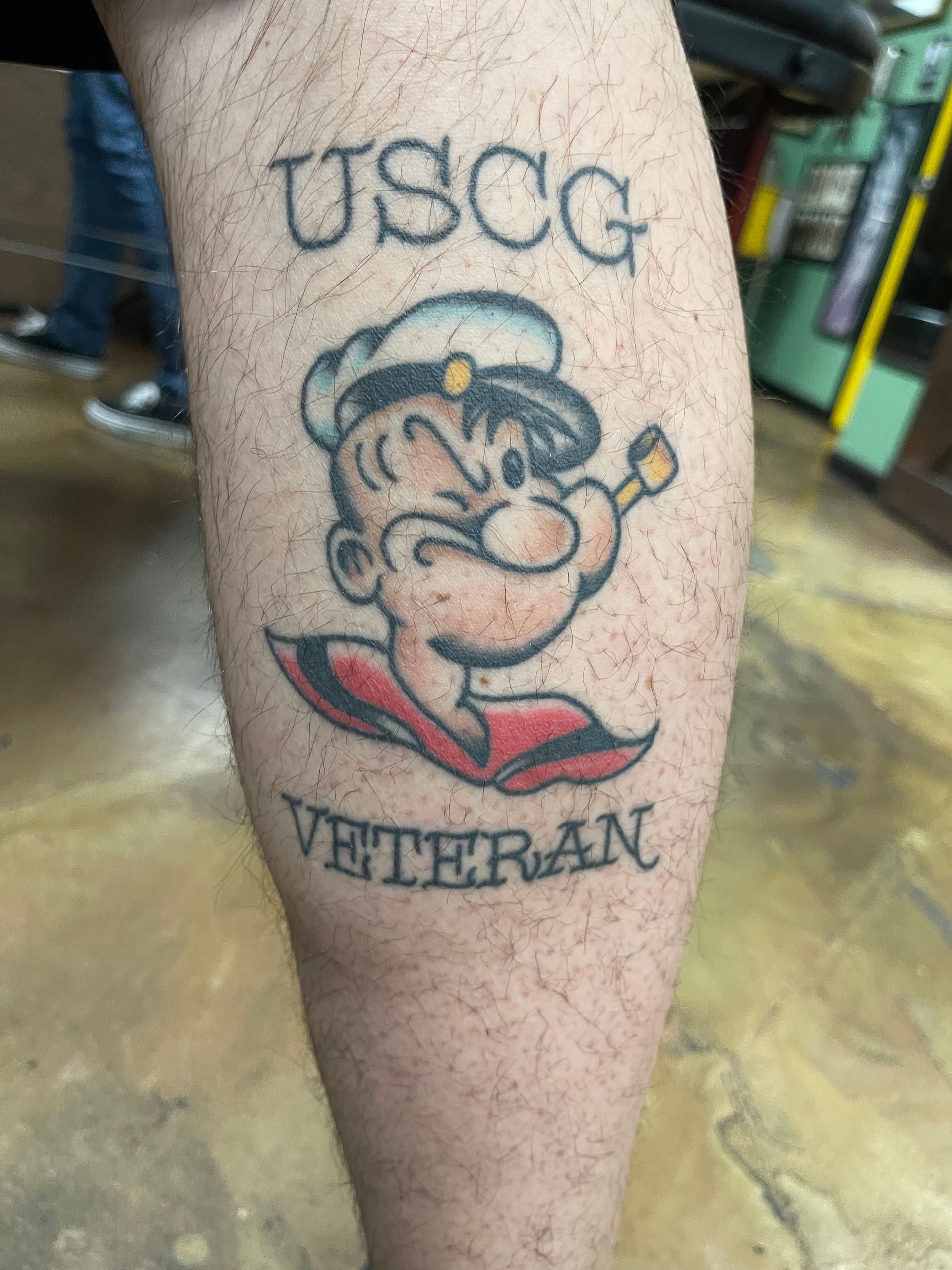 Tattoo on a leg featuring Popeye the sailor with 