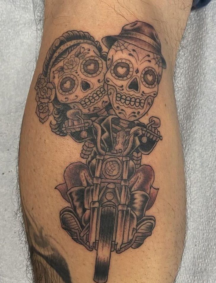 Tattoo of sugar skull couple on a motorcycle. Gray, black, and red ink. Cartoon style.