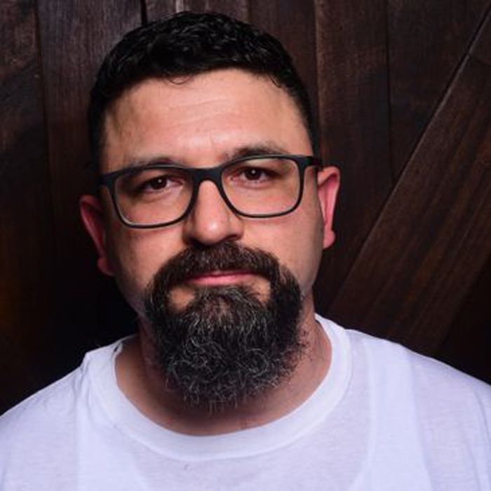 A man with a beard and glasses is wearing a white shirt.