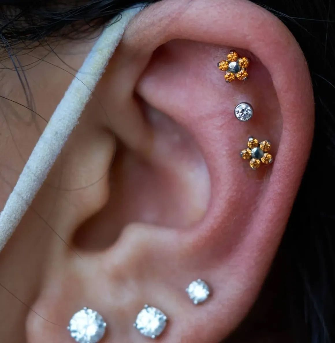 A close up of a woman 's ear with multiple piercings