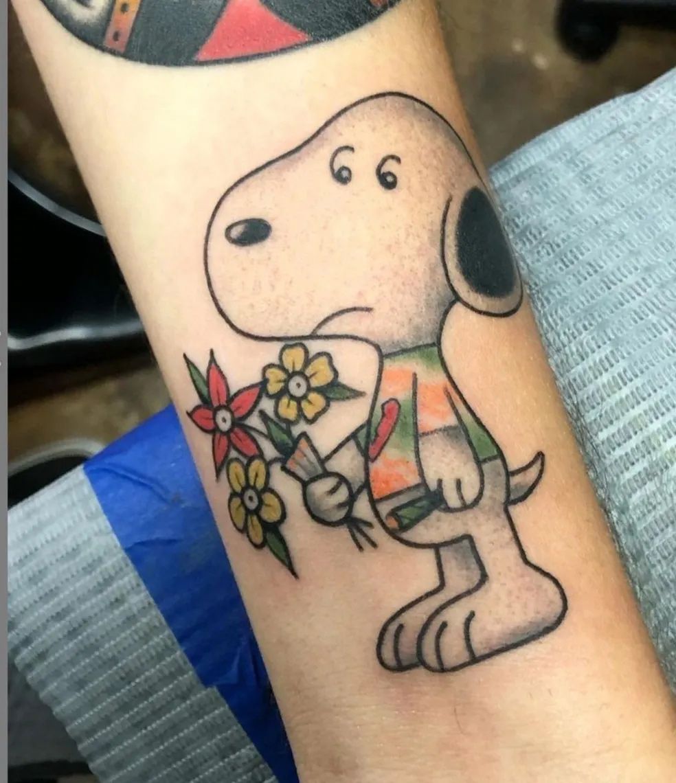 A person has a tattoo of snoopy holding flowers