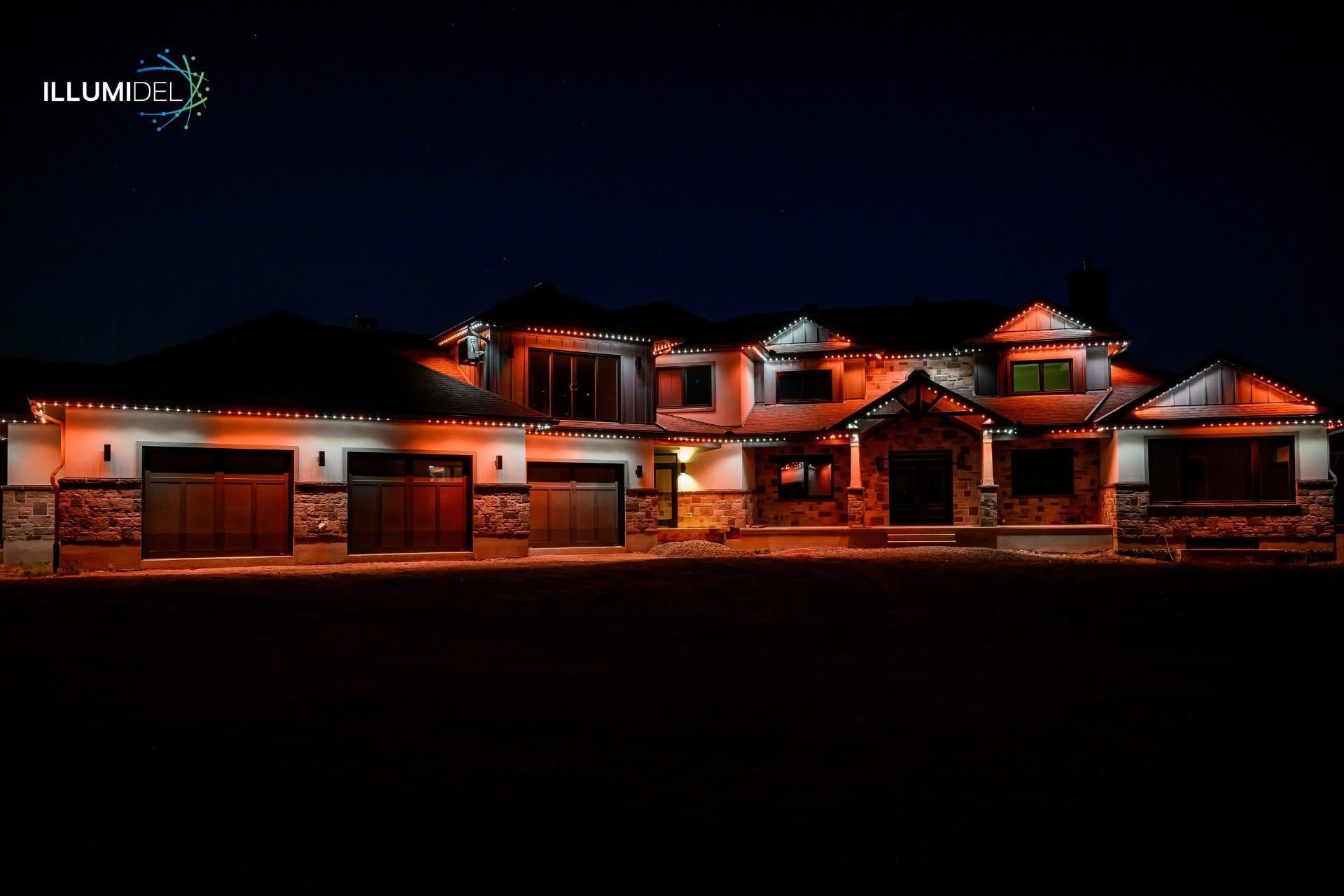 Large house illuminated with orange lights against a dark night sky.