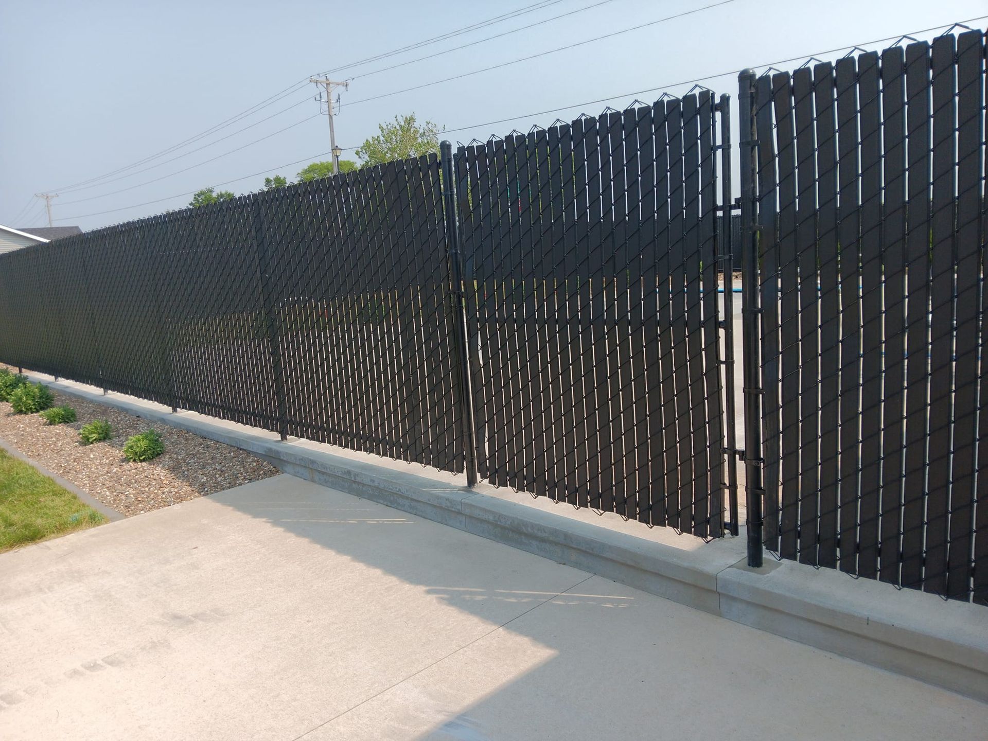 A black chain link fence is along a sidewalk