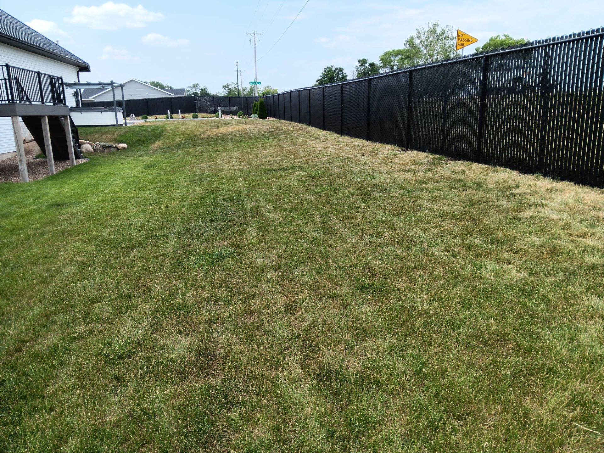 A black fence surrounds a lush green lawn in a backyard.