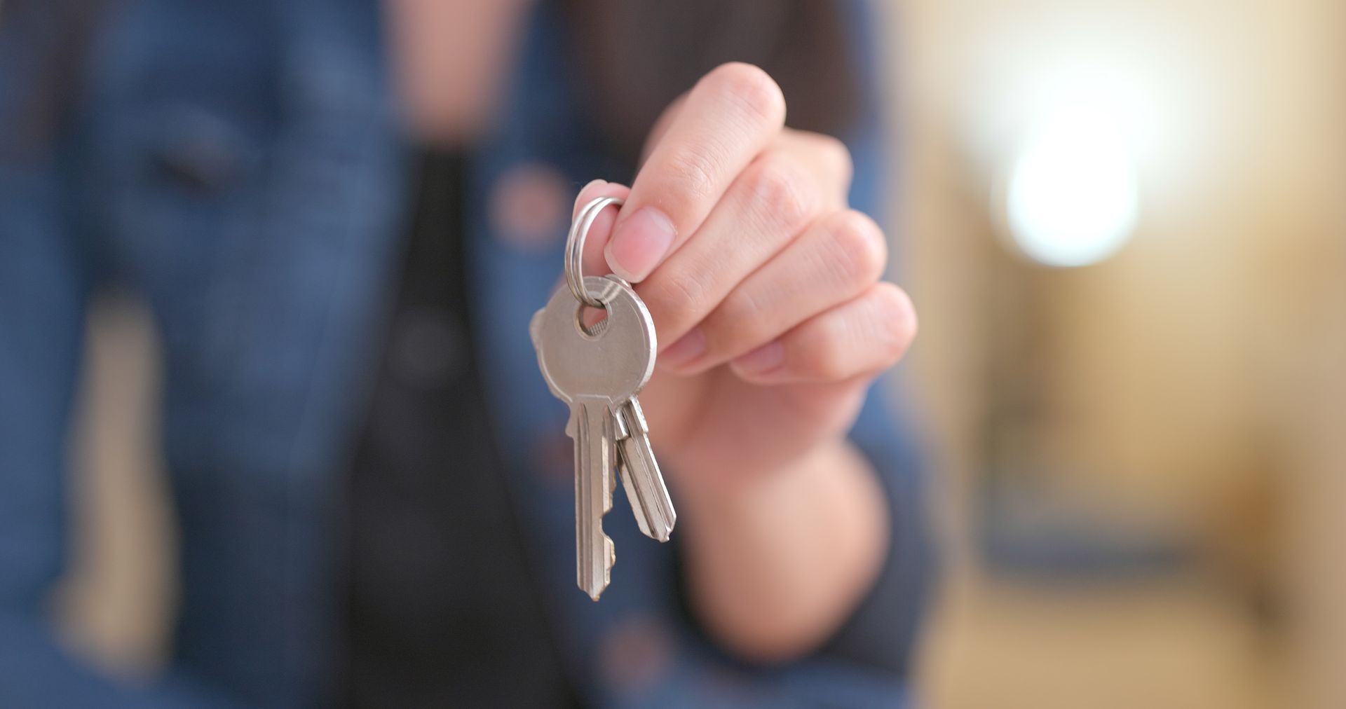 Hand holding up a set of keys with a blurred indoor background