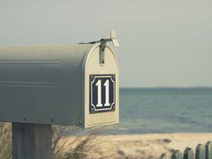 Red mailbox with open door on white post beside a house exterior.