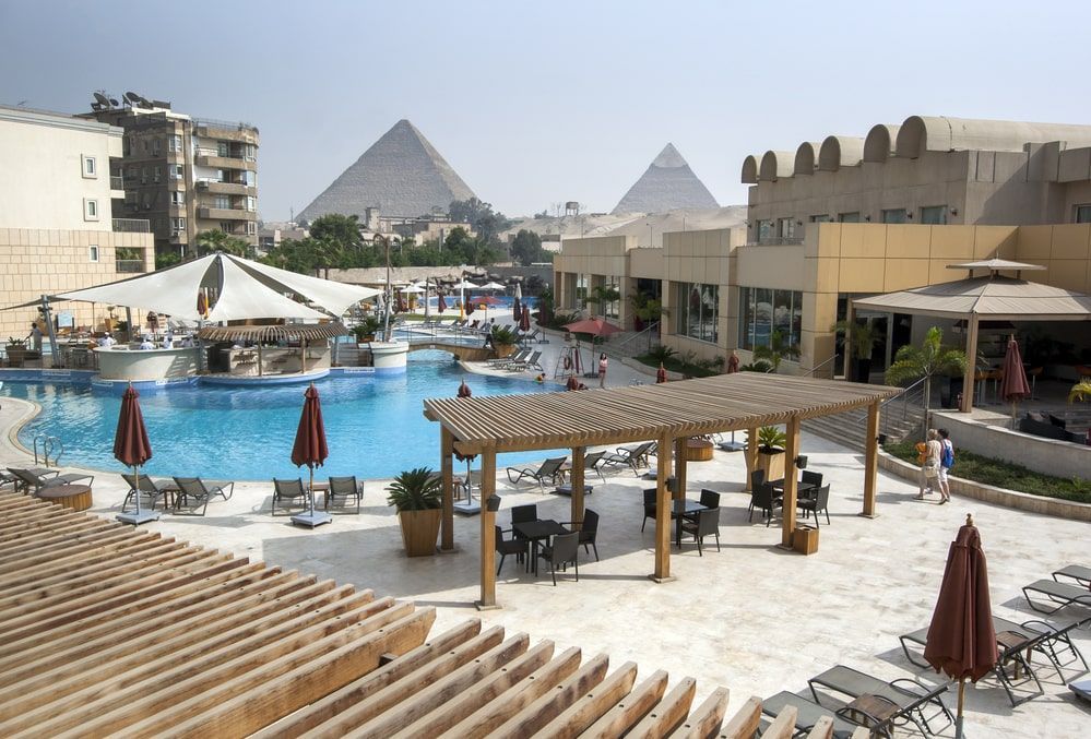 A+view+from+a+hotel+swimming+pool+in+the+late+afternoon+looking+towards+the+Pyramids+of+Giza+at+Cairo.jpg