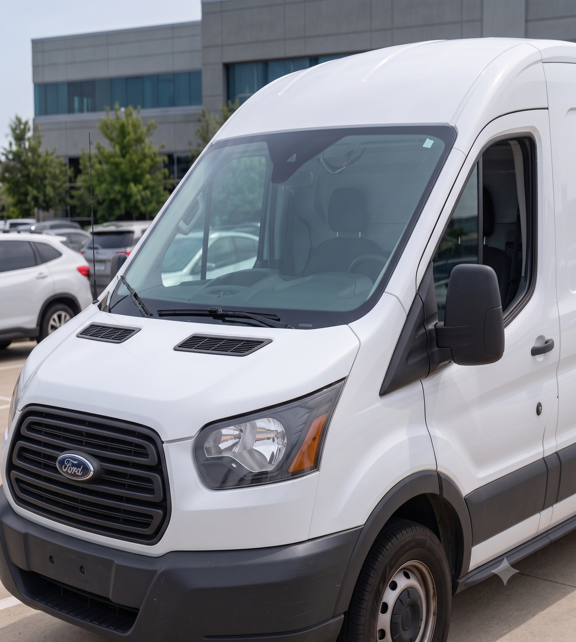White cargo van parked outside a modern office building on a sunny day