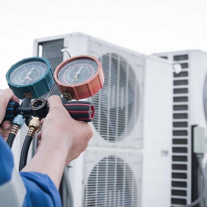 A person is holding two gauges in front of a building.