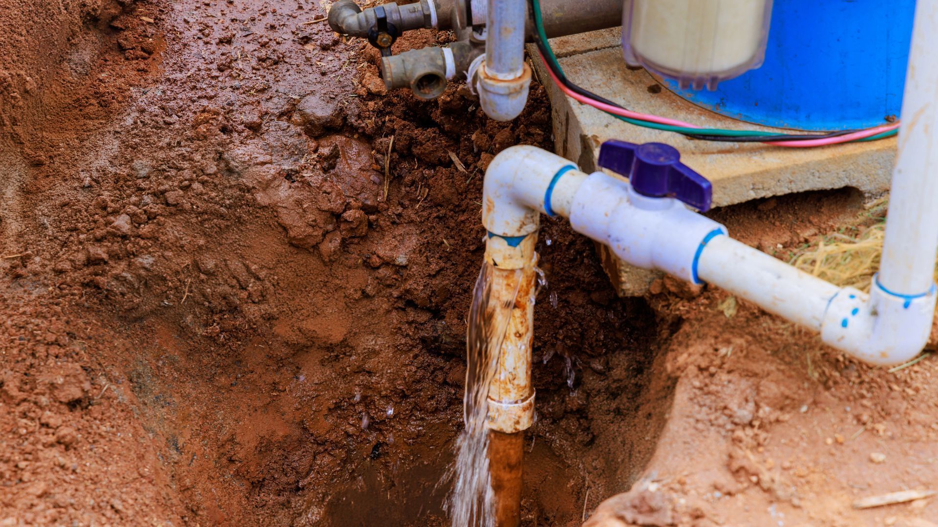 A water pump is being installed in a hole in the ground.