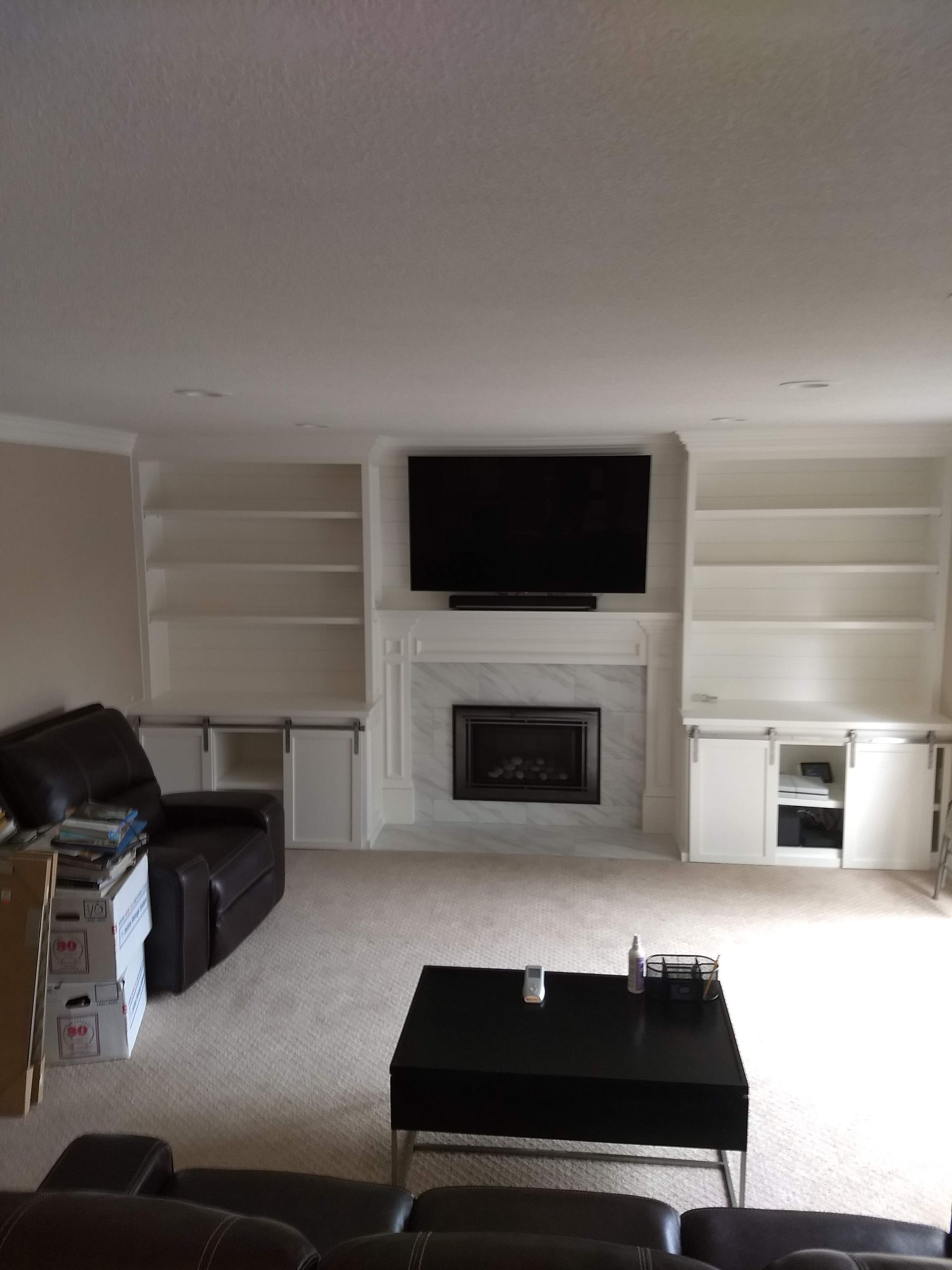 Living room with fireplace, wall-mounted TV, sofa, coffee table, and built-in shelves