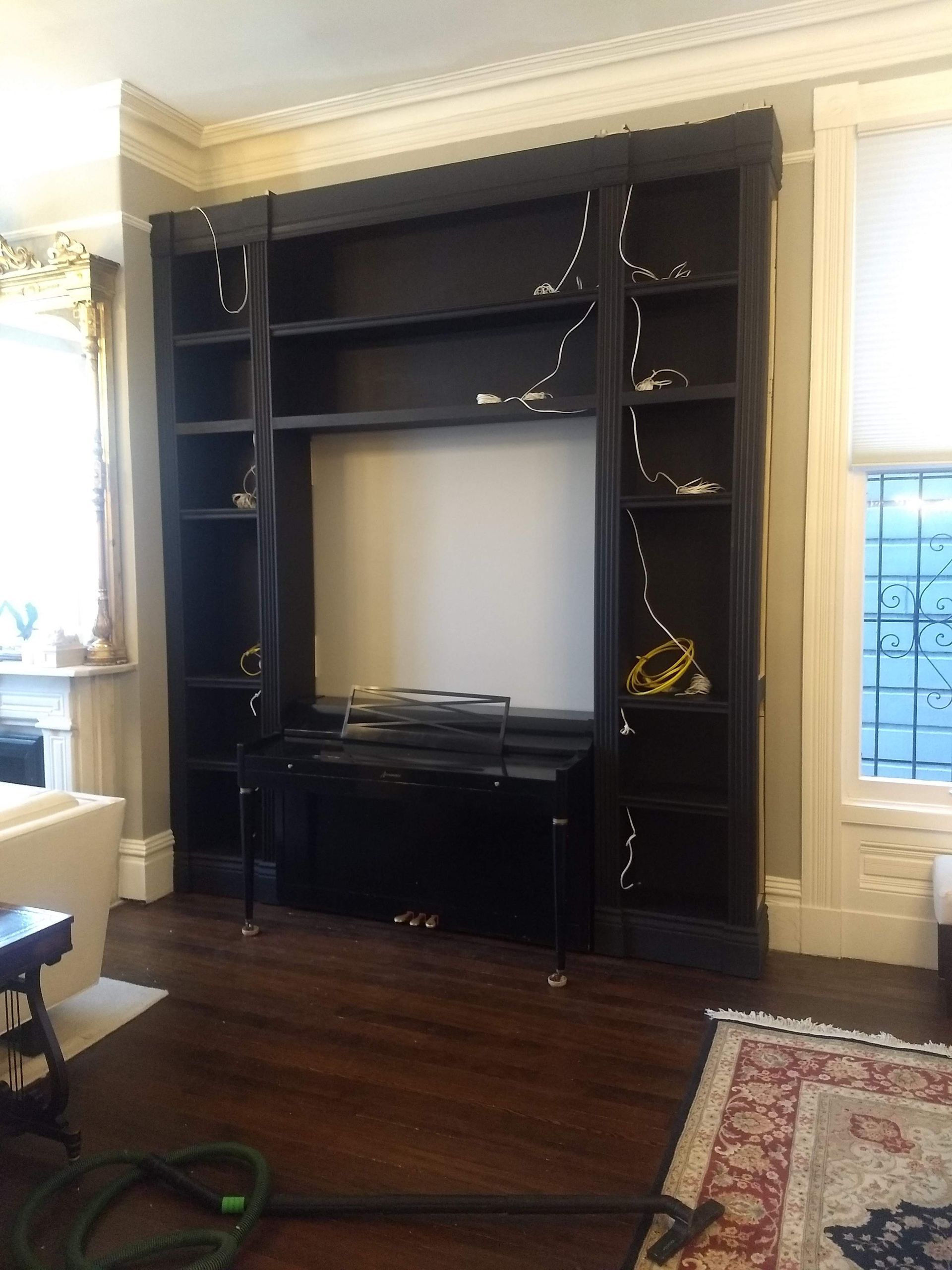 Black entertainment center with TV, shelves, and string lights in a living room