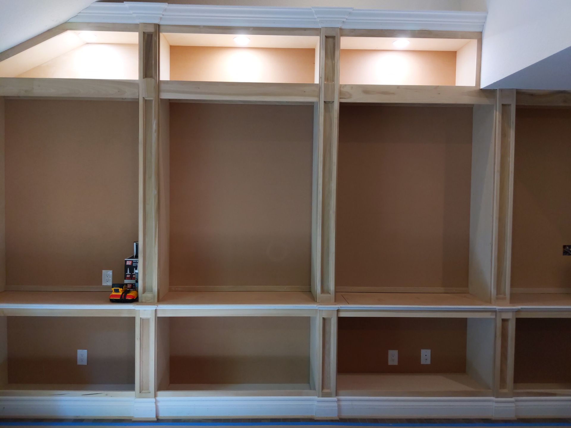 Built-in wall shelving with white trim, beige back panels, and a few small items on the left shelf.