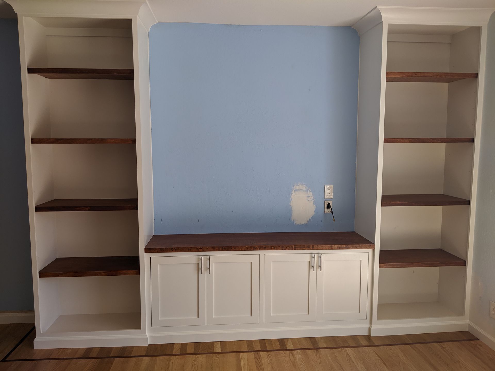 Built-in white shelves and cabinets with a light blue alcove in the center