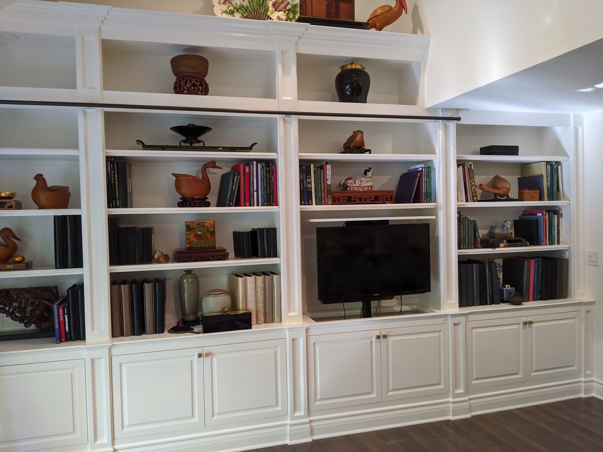 White built-in wall unit with books, decor, and a TV in a living room