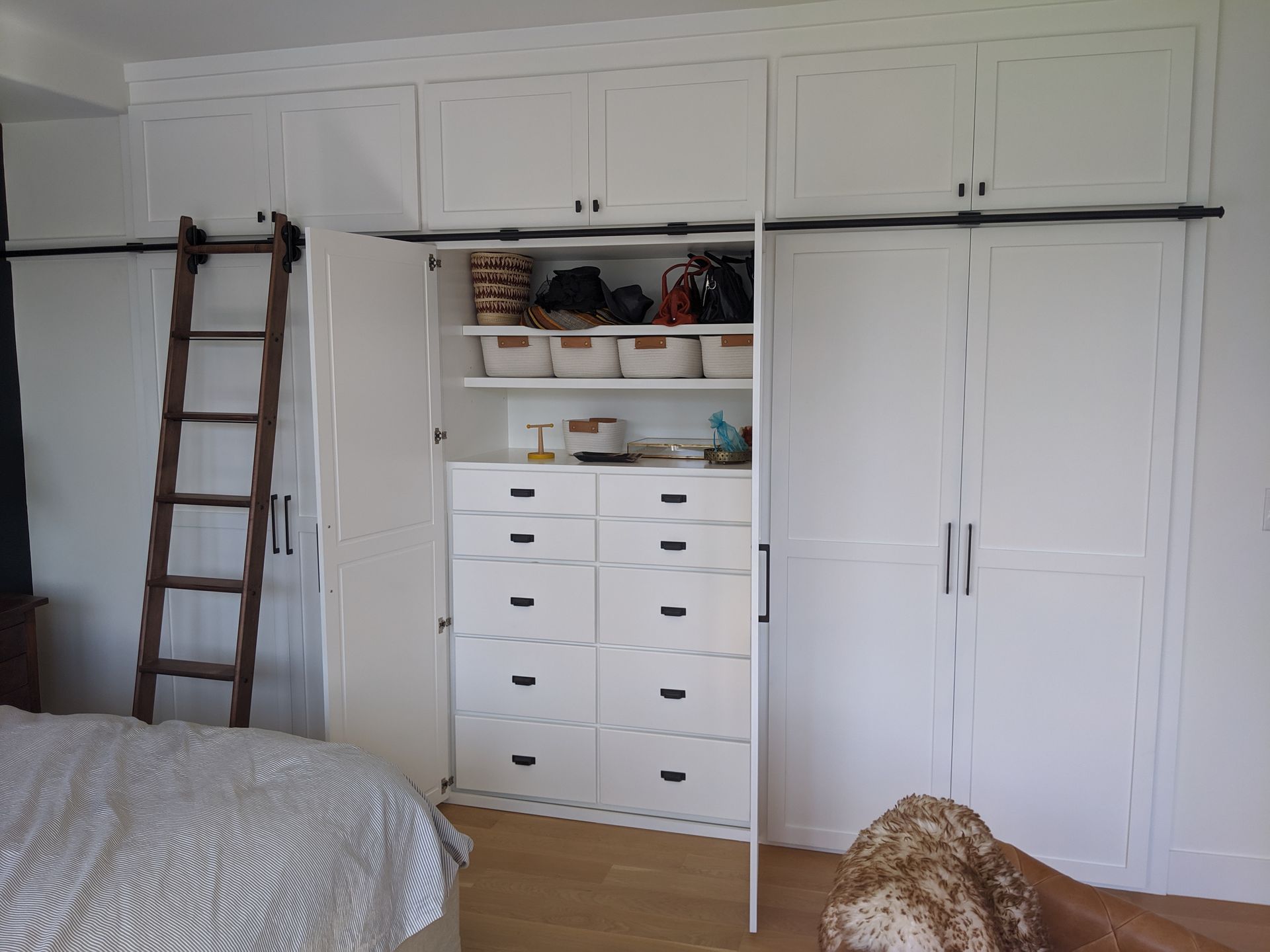 Bedroom with white built-in wardrobes, dresser, and a wooden ladder on the left wall.
