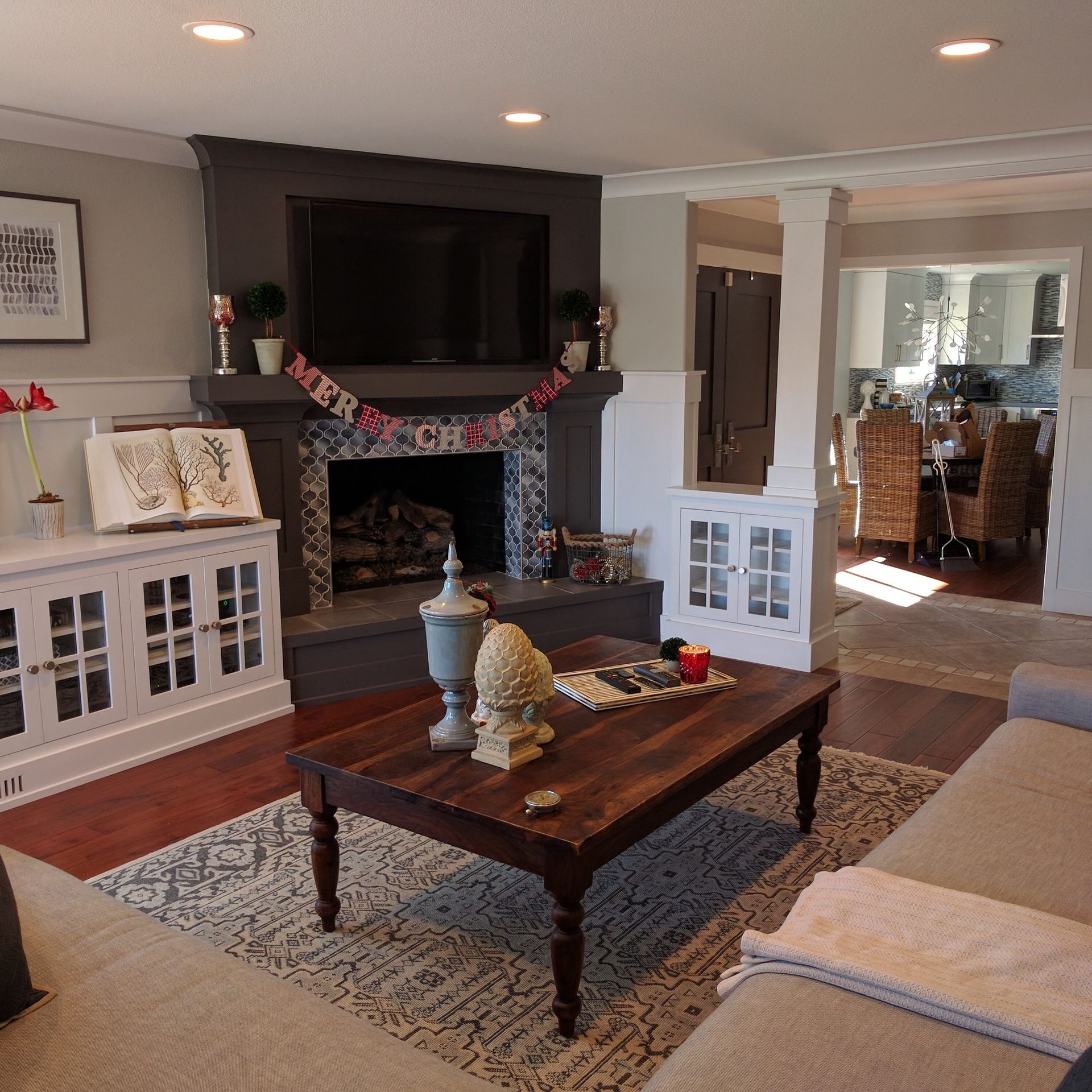 Cozy living room with fireplace, wall-mounted TV, coffee table, and white cabinets beside a sofa