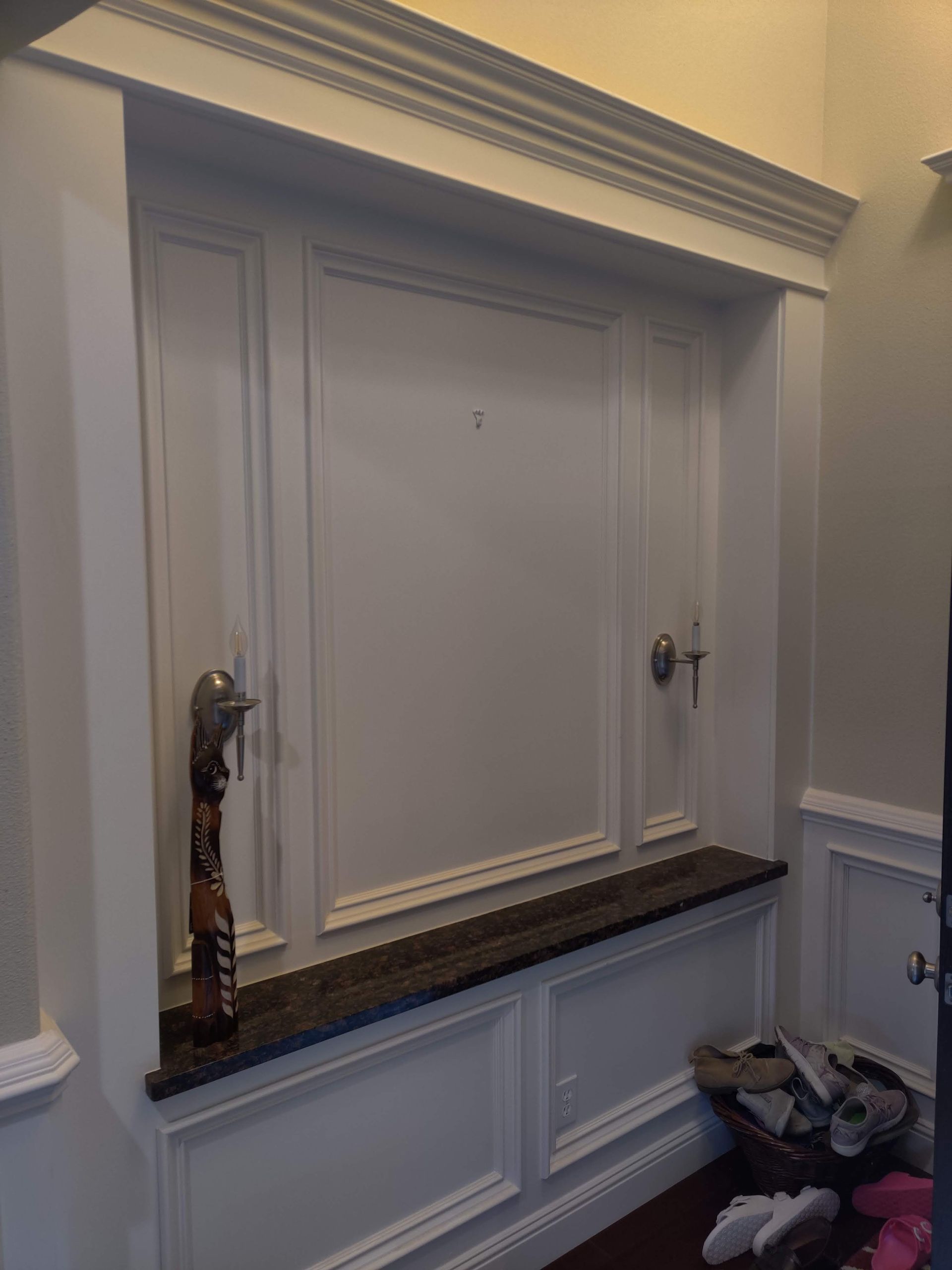 White recessed wall niche with dark countertop and decorative wall sconces in a hallway