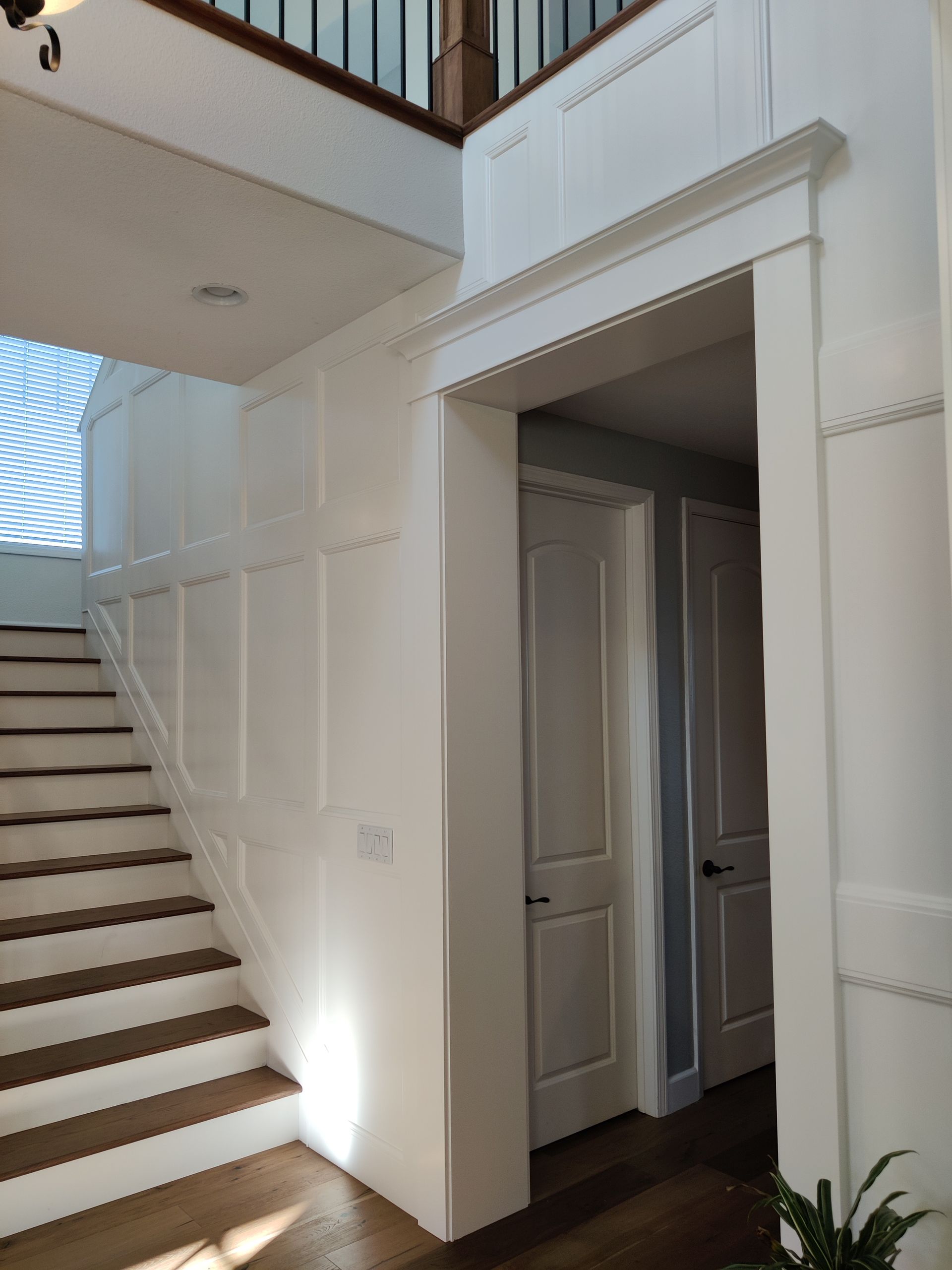 White staircase and hallway with an open doorway leading to a small room or closet